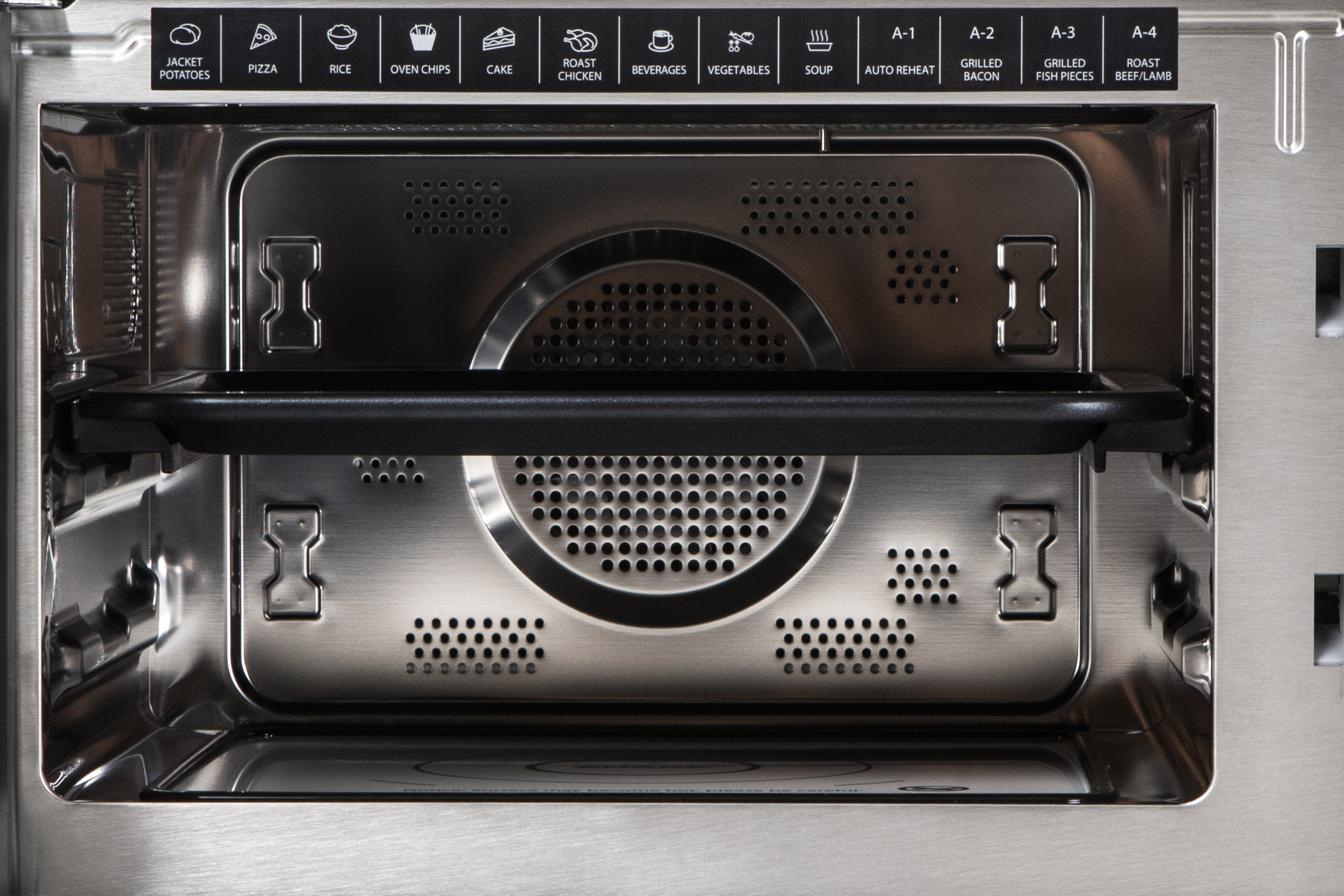 Inside of a microwave oven.  Stainless steel interior with various function icons.