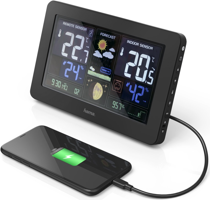 Stazione meteo nera con display che mostra temperatura, umidità e previsioni. Telefono in carica.