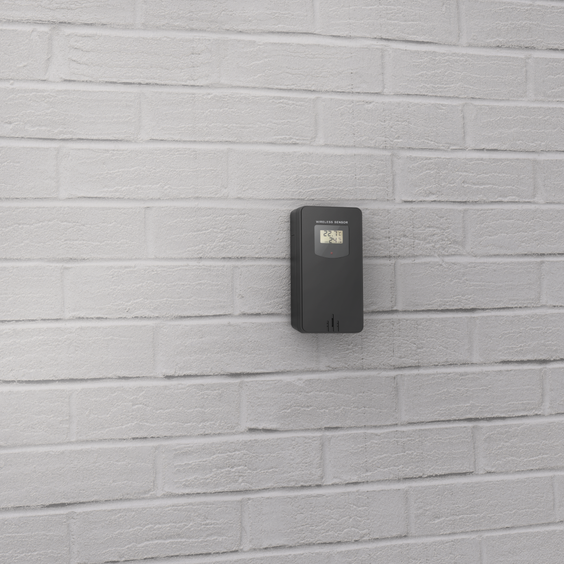 Un sensore wireless nero e rettangolare attaccato a un muro di mattoni bianchi, che mostra la temperatura.