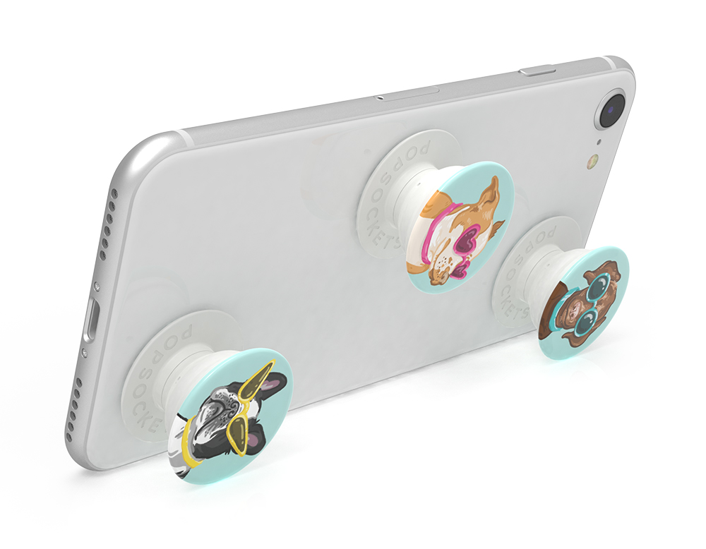 Un smartphone blanc avec trois PopSockets attachés, présentant des motifs de chiens de dessin animé.