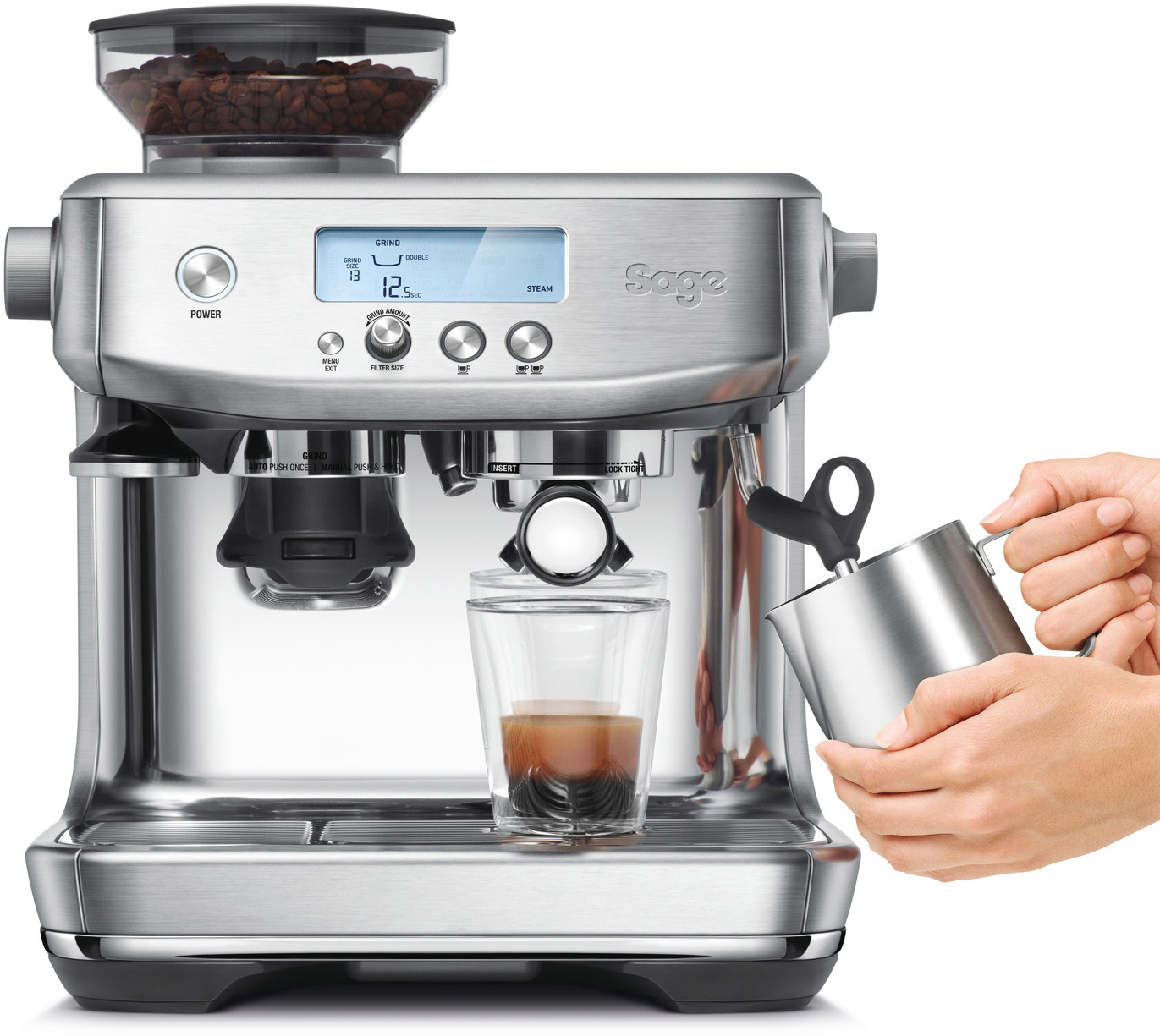 Silberne Espressomaschine. Ein Glas hat Espresso und der Barista schäumt Milch auf.