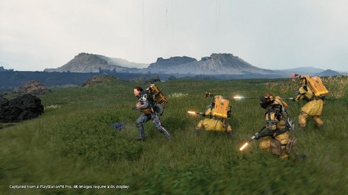 Escena de acción de un videojuego con personajes con trajes amarillos corriendo por un campo.