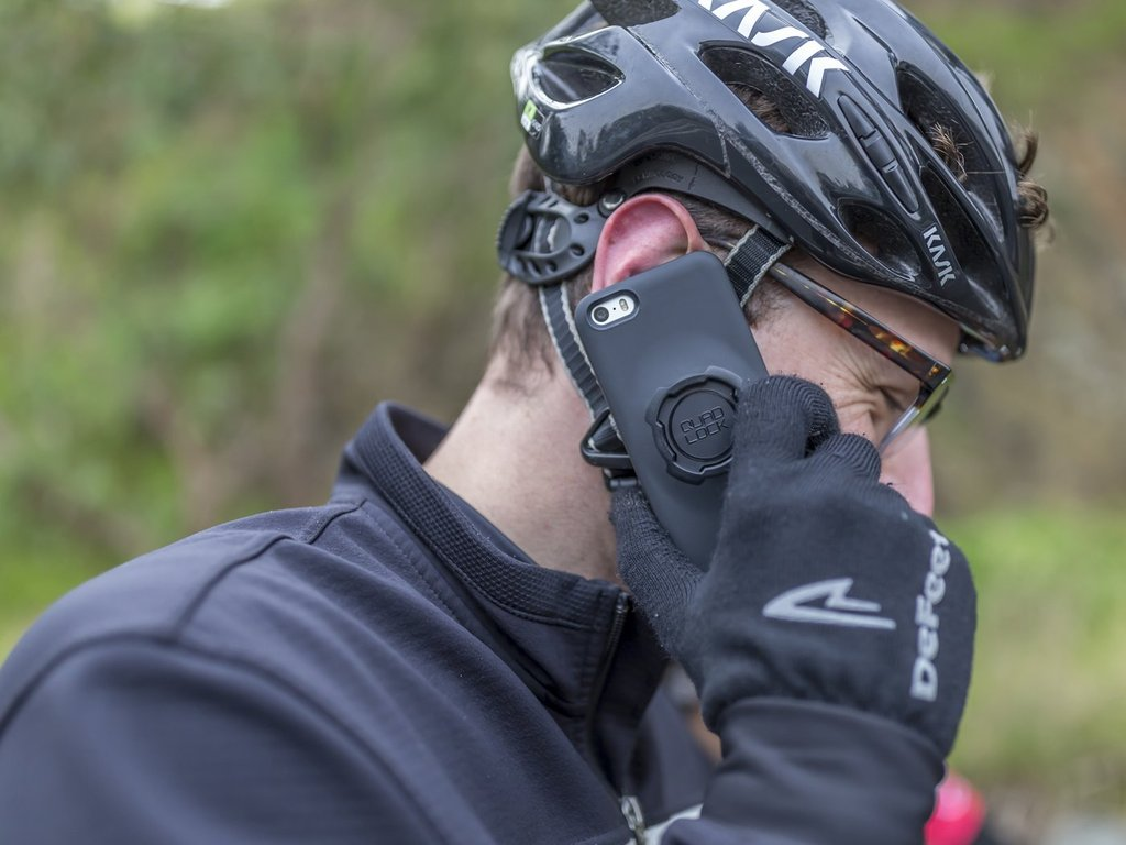 Radfahrer mit Helm und Handy am Ohr.