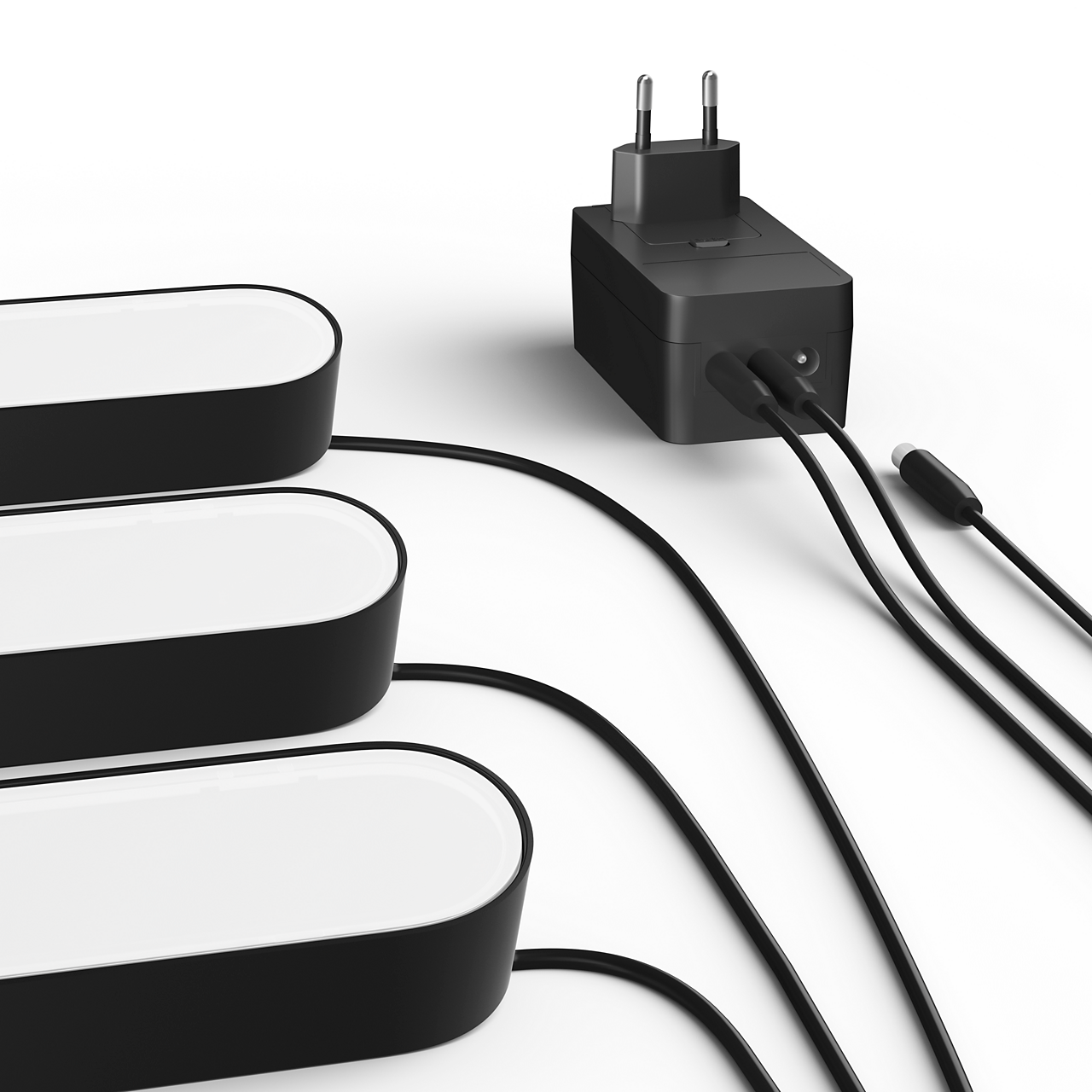 Three black, elongated lights are connected to a black power adapter with a plug and black cables.