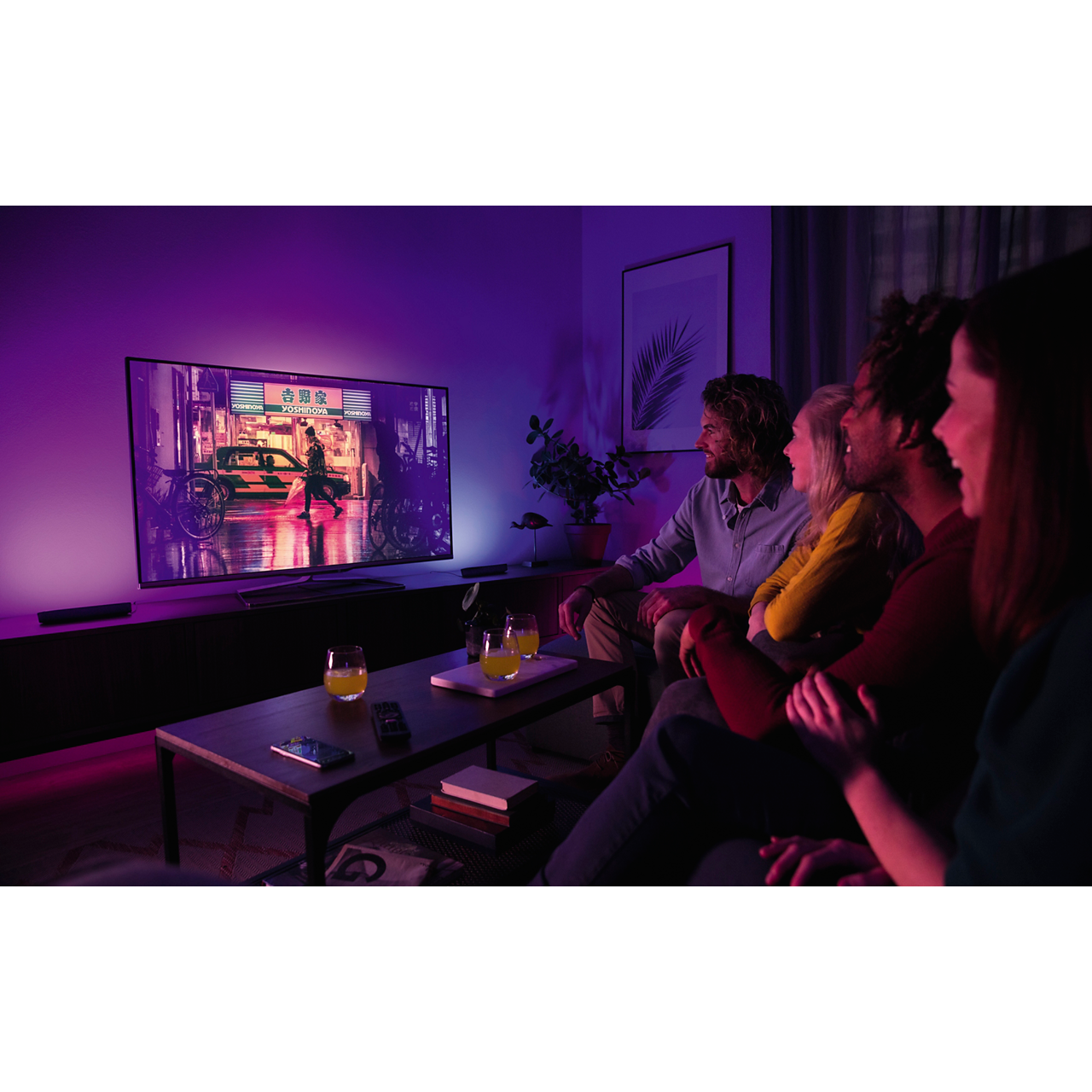People watch TV with a neon-lit scene. Drinks on the table. Purple ambient light.
