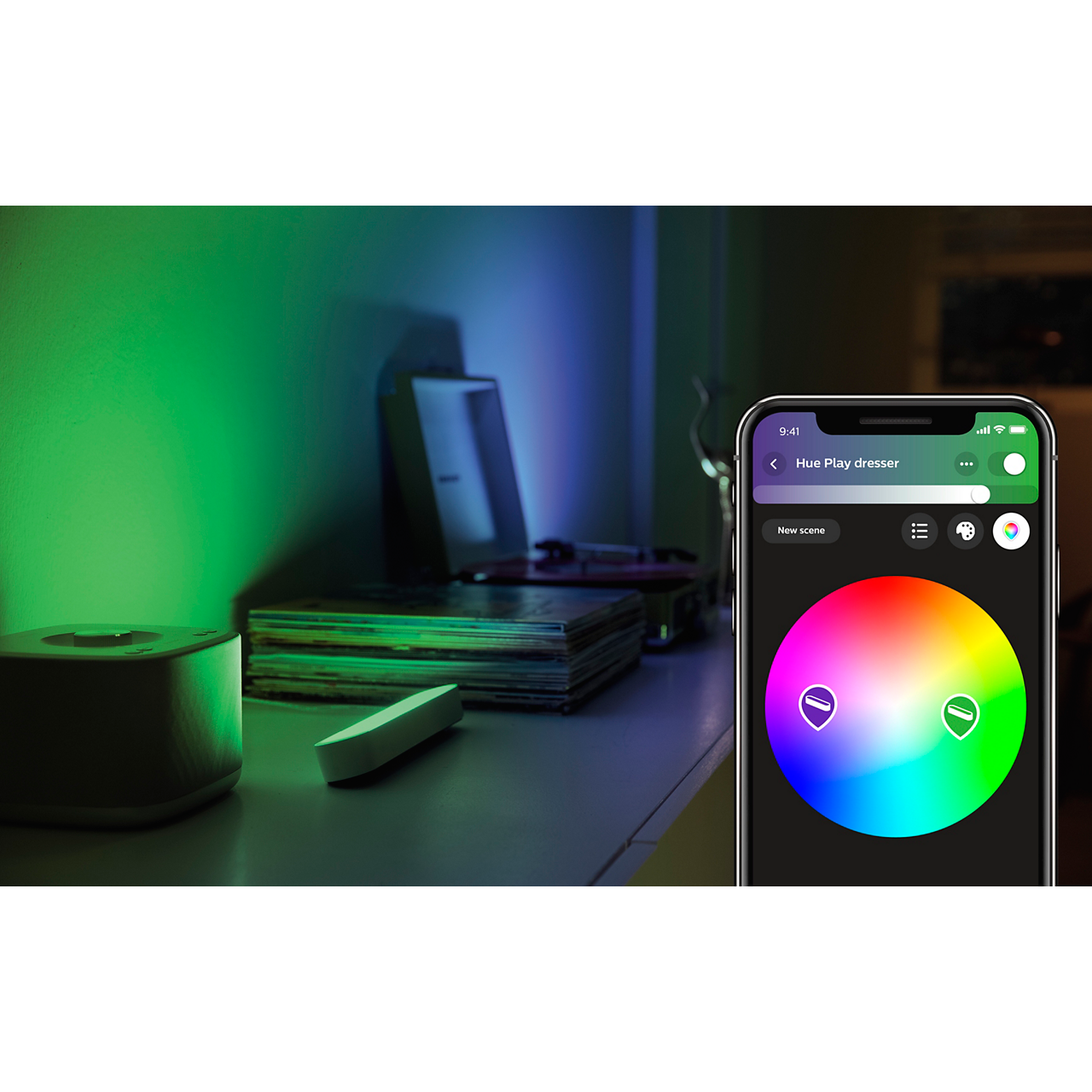 Smart home scene with colored lights and a smartphone. The phone displays a color wheel.