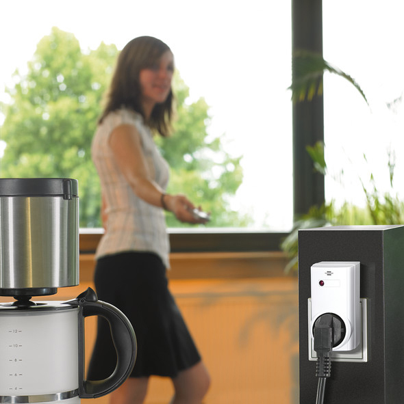 Frau geht an Kaffeemaschine und Steckdose vorbei.