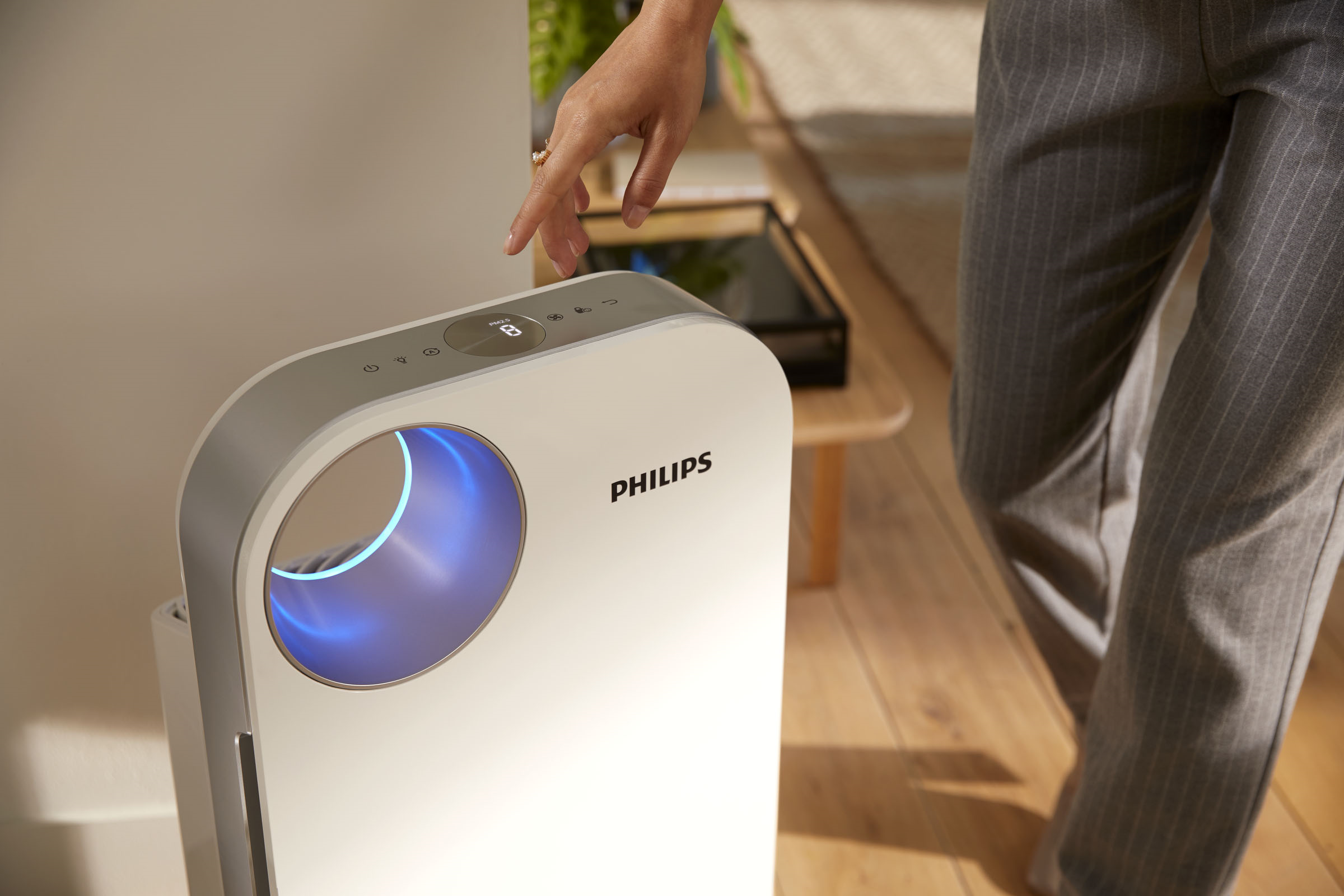 Eine Hand berührt das Bedienfeld eines weißen Philips Luftreinigers.