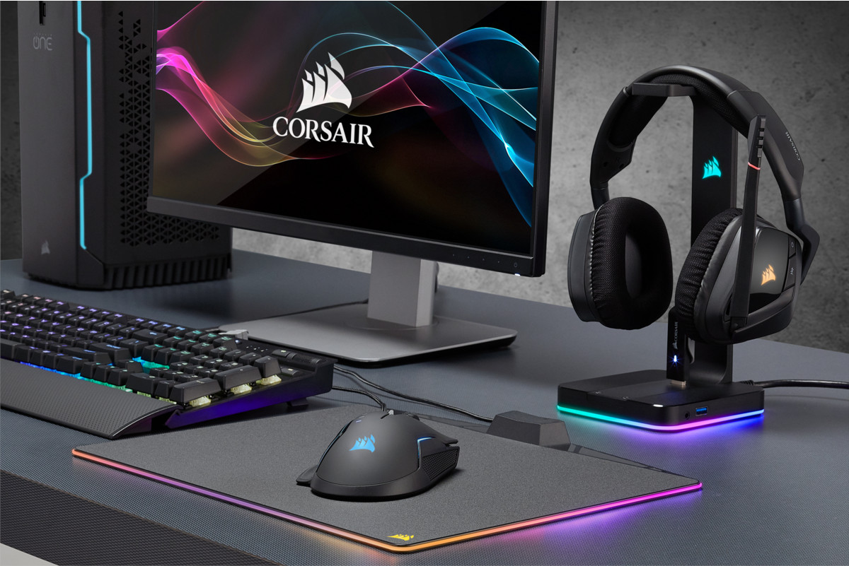 A gaming setup with a monitor, keyboard, mouse, headset, and mousepad. Corsair brand is visible.