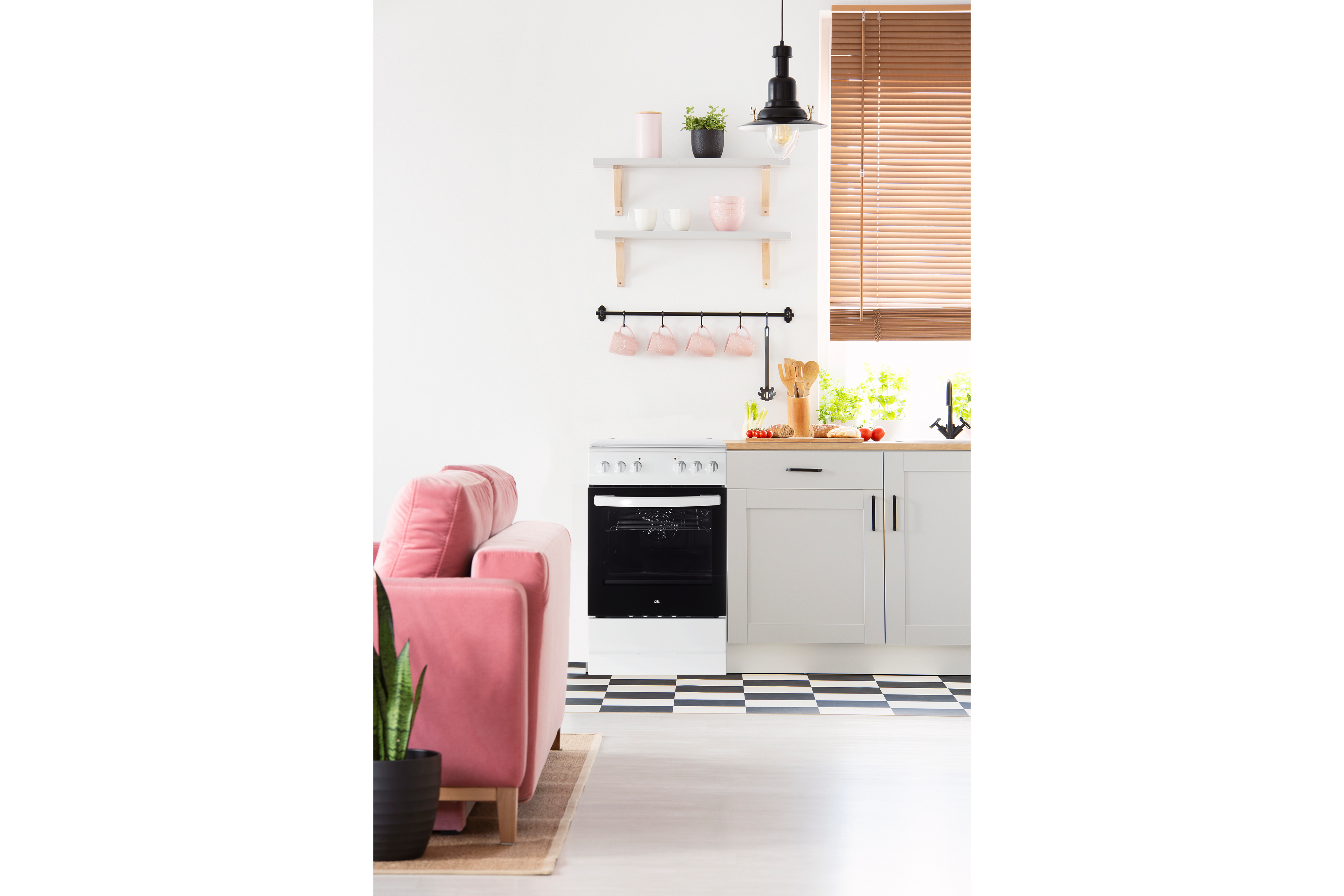 Moderne Küche mit weißem Schrank, schwarz-weiß kariertem Boden, rosa Sofa und weißem Backofen.