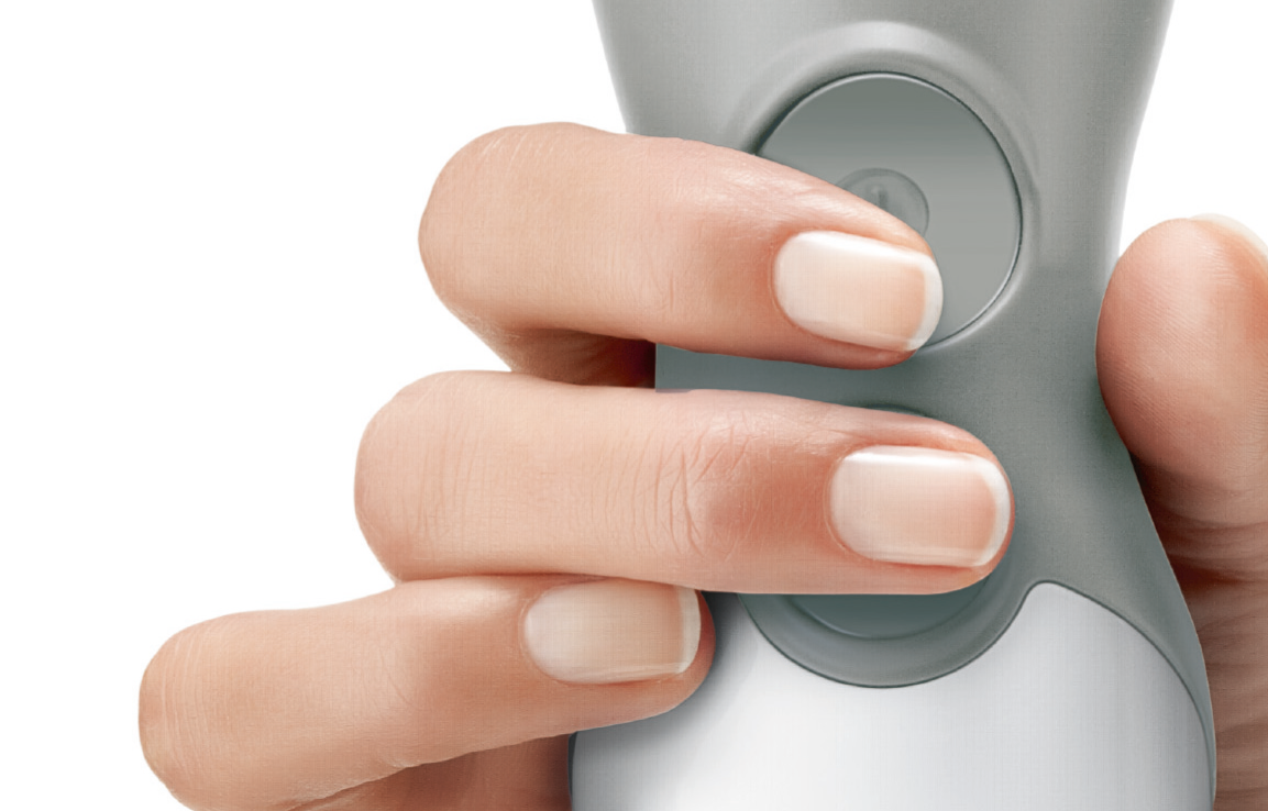 Hand hält einen grau-weißen Handmixer und drückt mit einem Fingernagel auf eine Taste.
