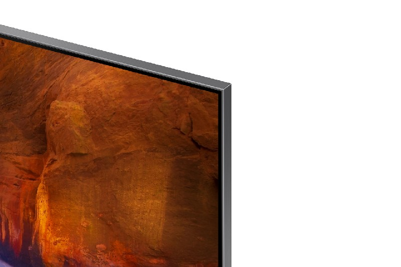 Primer plano de una pantalla de TV gris oscuro con un paisaje marrón y naranja visible. Bisel plateado.