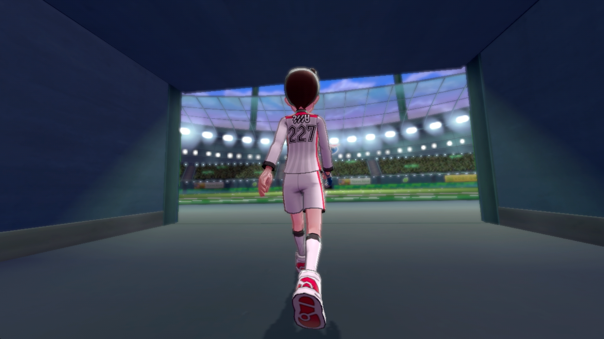 Una persona in uniforme da calcio cammina attraverso un tunnel dello stadio, verso il campo.