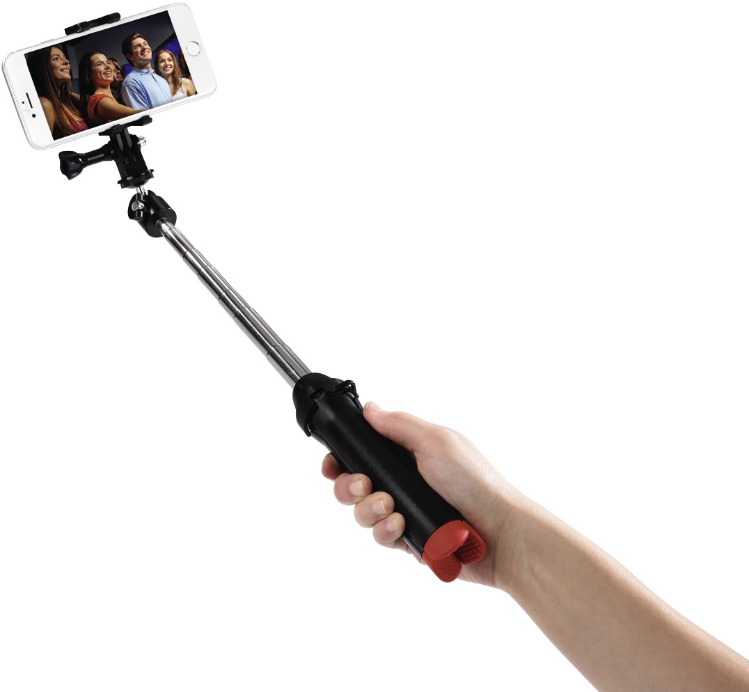 Main tenant une perche à selfie avec un téléphone affichant des personnes souriantes.