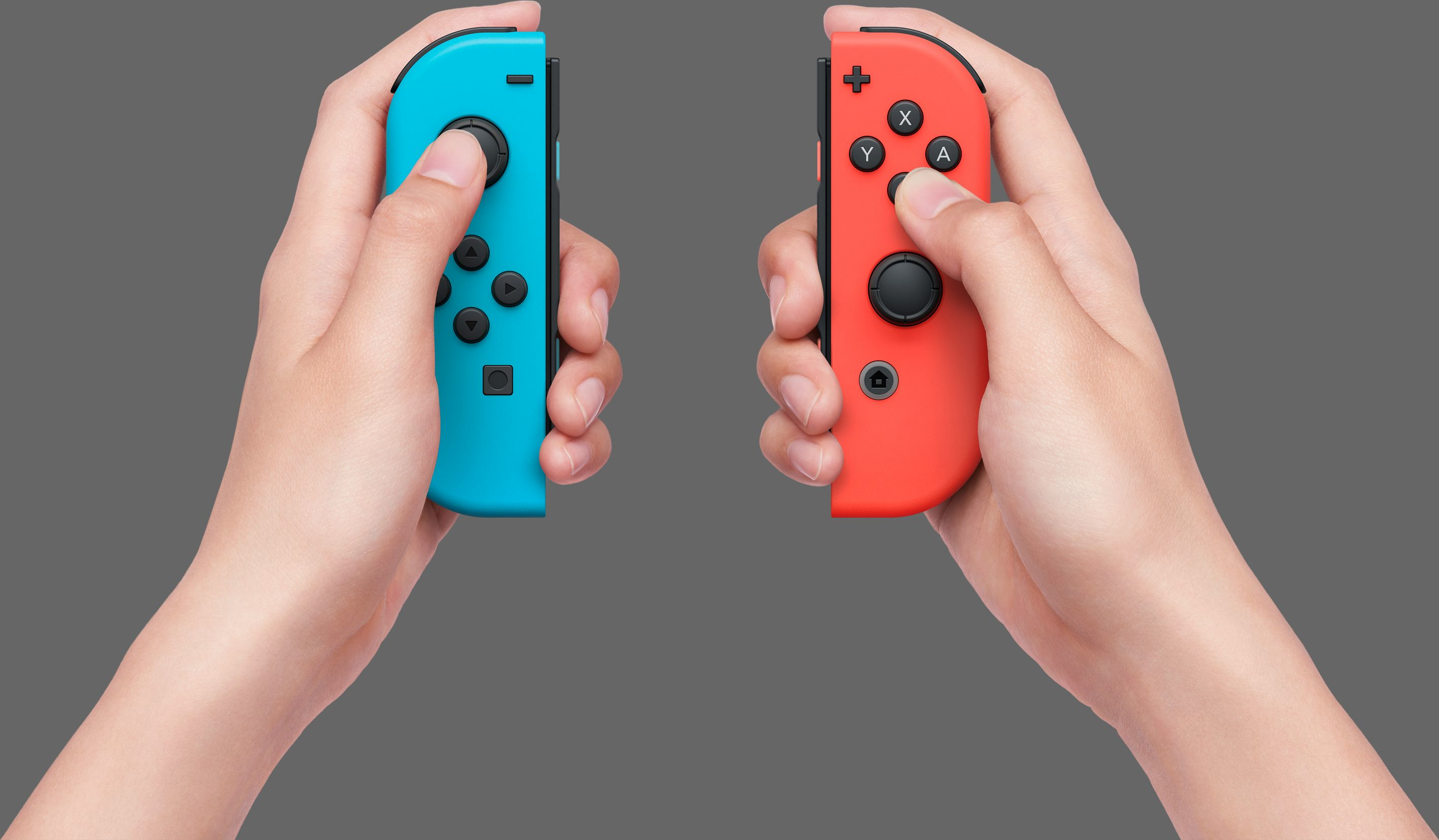 Hände halten zwei Nintendo Switch-Controller, einen blauen und einen roten. Grauer Hintergrund.