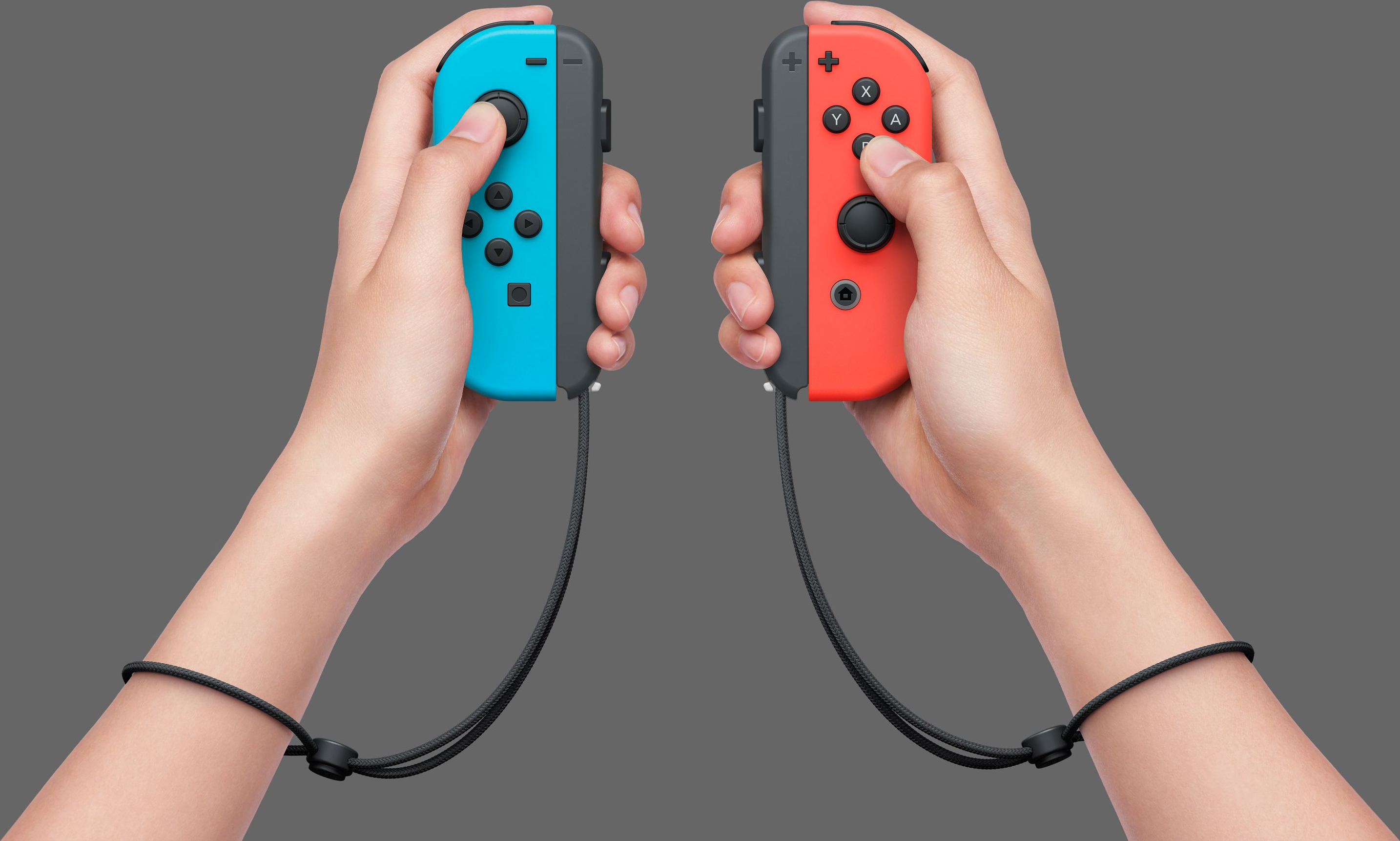 Hände halten blaue und rote Nintendo Switch Joy-Cons mit Handschlaufen, vor grauem Hintergrund.
