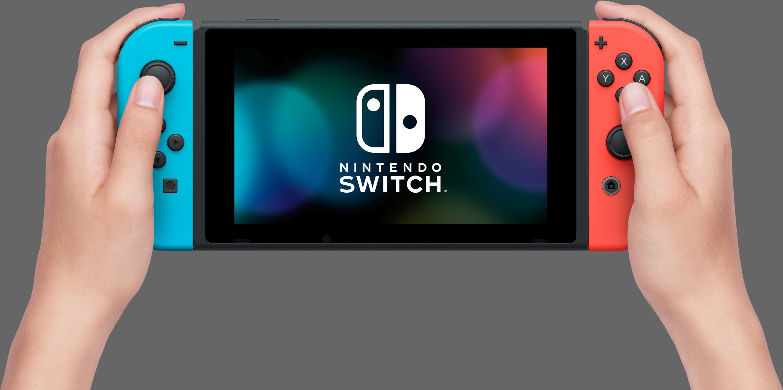 Hände halten eine Nintendo Switch. Der linke Joy-Con ist blau und der rechte rot. Der Bildschirm zeigt das Nintendo-Logo.