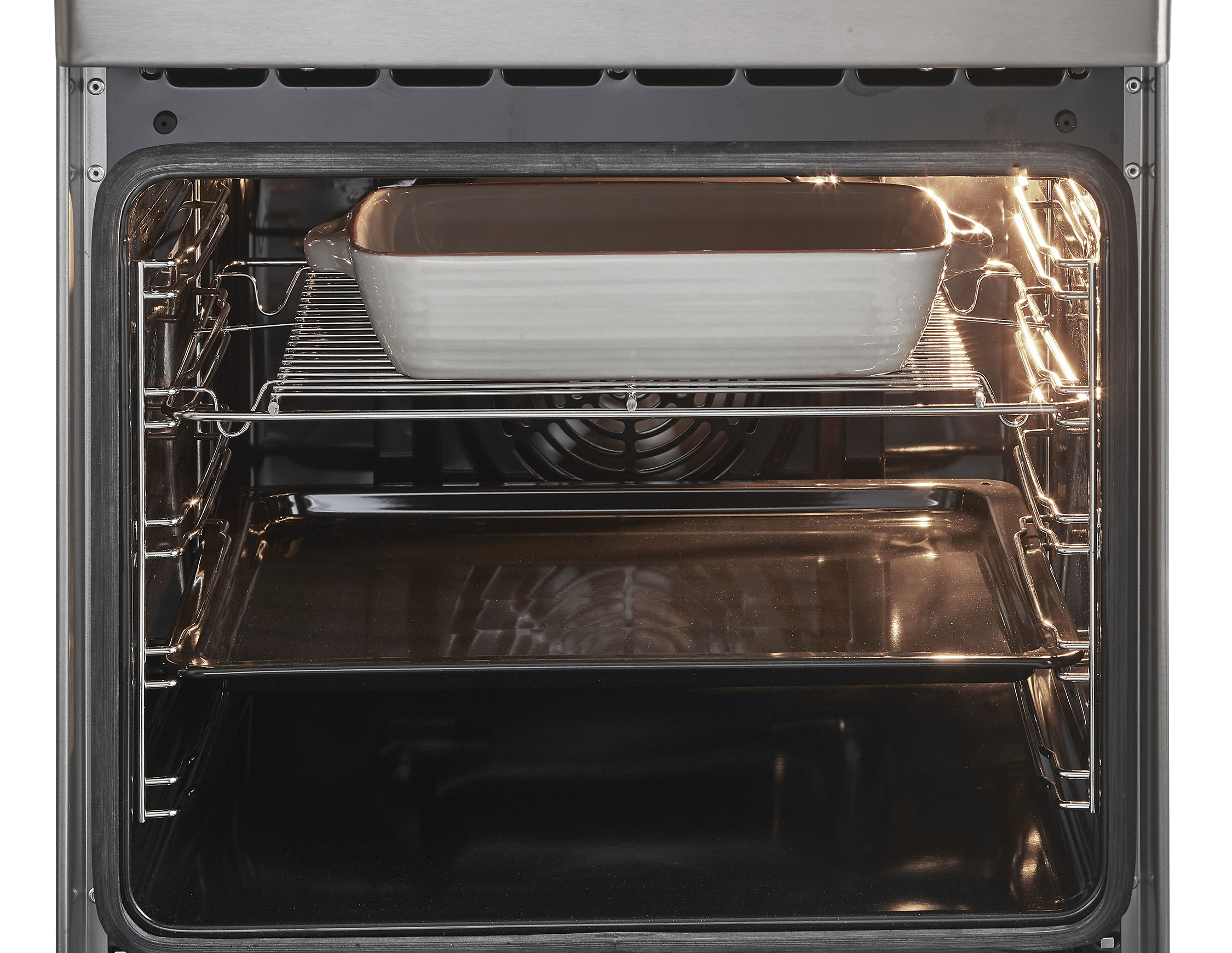 Inside of an oven with a casserole dish on the rack and a tray below. Bright light.