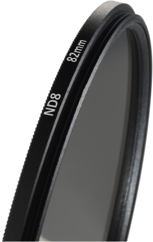 Gros plan sur un filtre d'appareil photo ND8 82mm noir. Il a des bords noirs et un centre en verre gris, isolé sur blanc.
