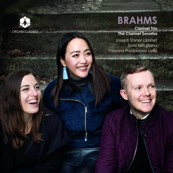 Albumcover mit drei lächelnden Musikern: zwei Frauen und ein Mann.