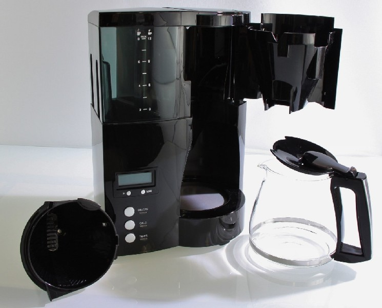 Una cafetera negra con una jarra de vidrio y partes del filtro.