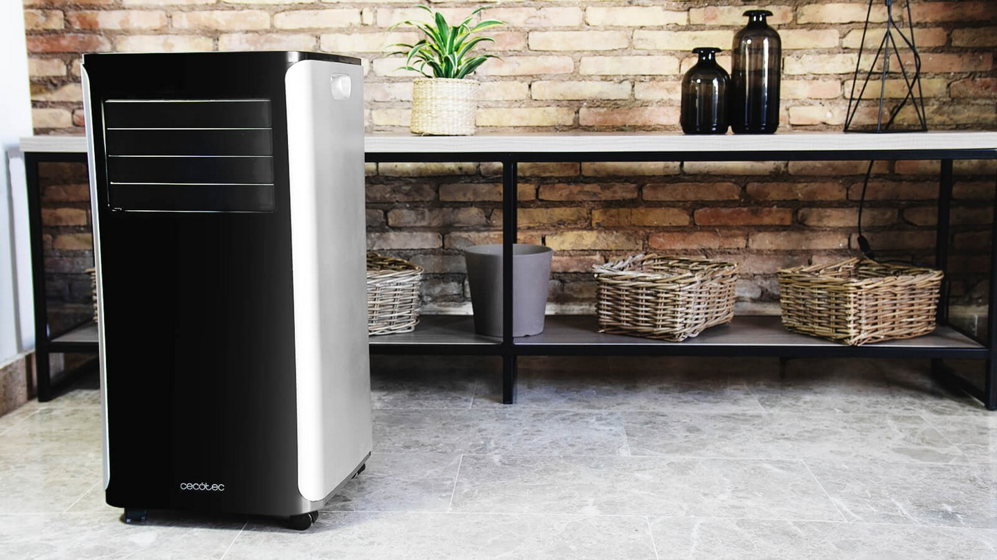 Enfriador de aire negro y plateado, colocado junto a un estante con decoraciones y pared de ladrillo.