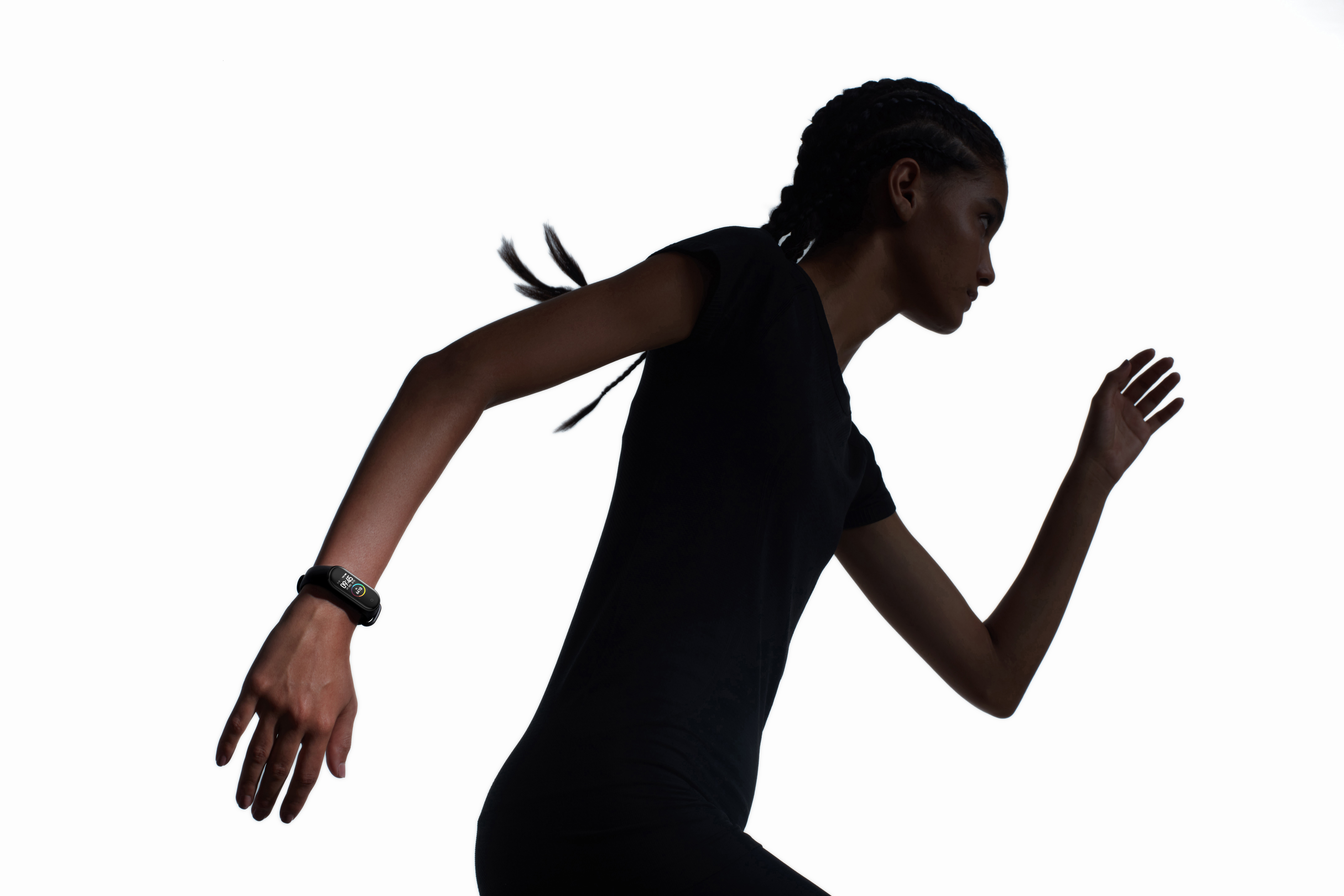 Eine Frau in schwarzer Sportkleidung rennt als Silhouette vor weißem Hintergrund. Ein Fitnesstracker ist sichtbar.