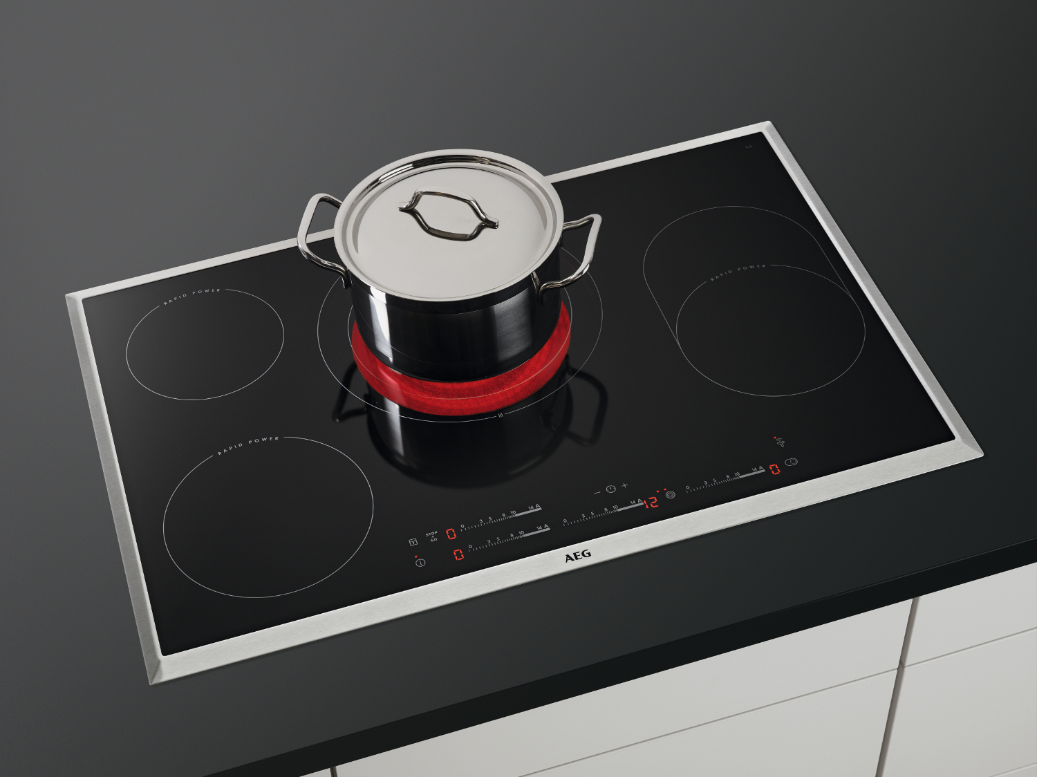 Plaque à induction noire avec une casserole sur un cercle rouge. Quatre feux.