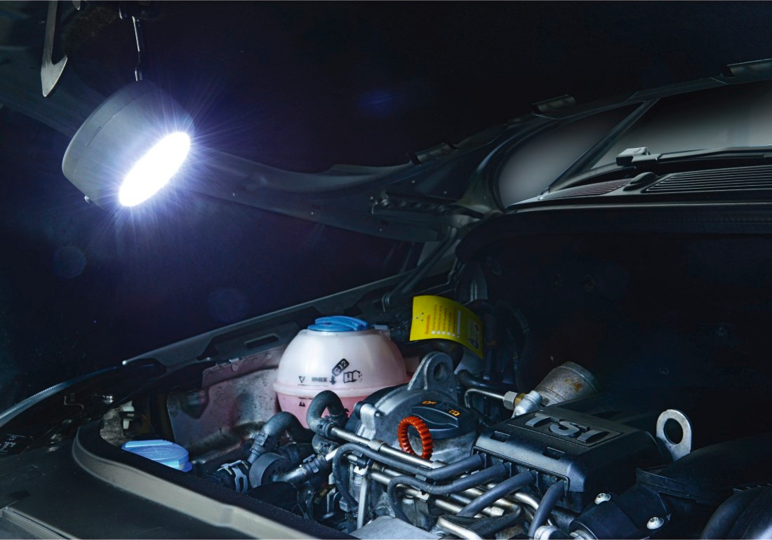 Compartiment moteur de voiture éclairé par une lampe de travail portable lumineuse.