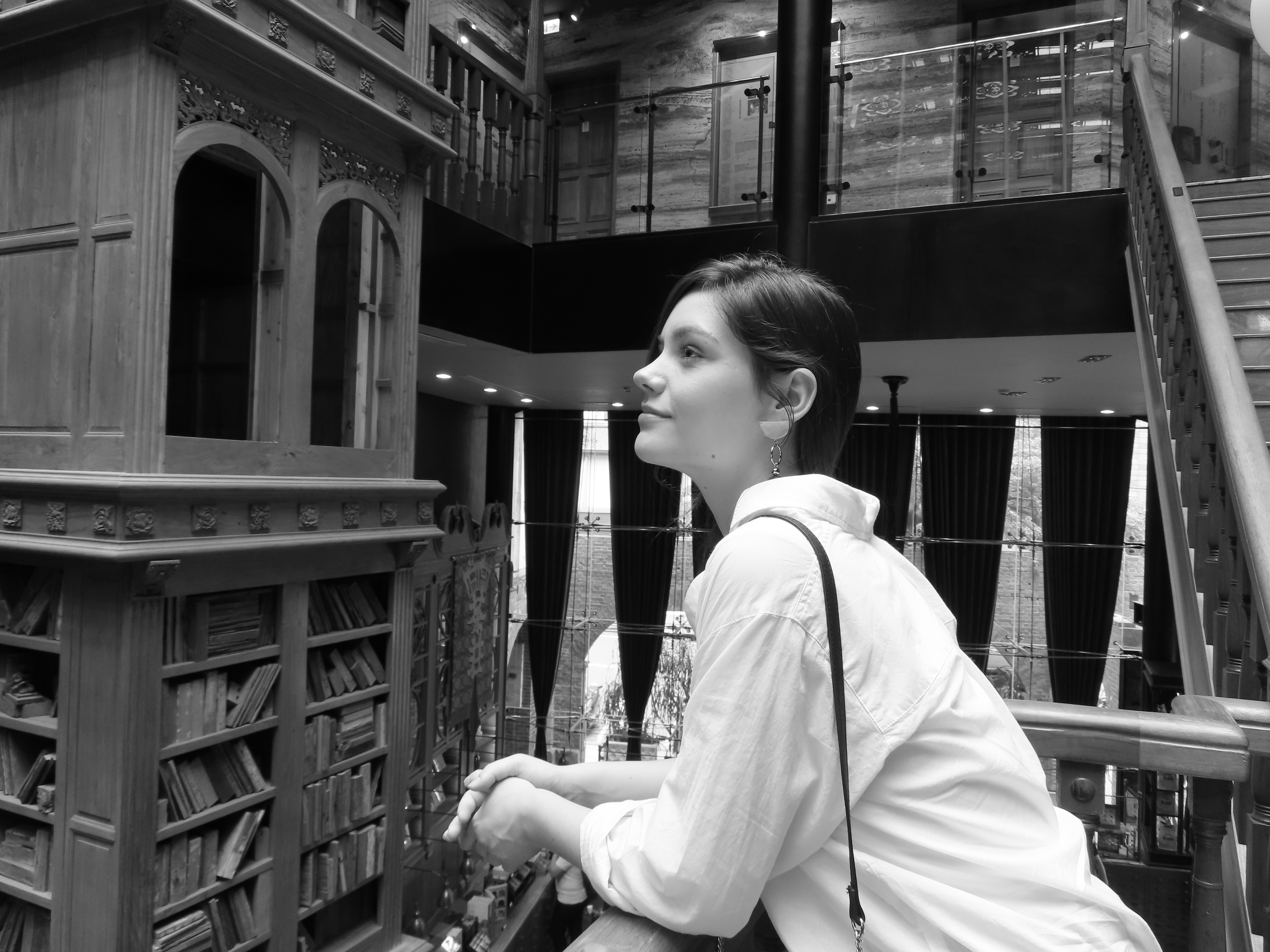Frau in einer Bibliothek, die zu den Regalen aufblickt.
