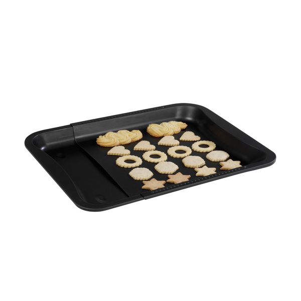 Schwarzes Backblech mit verschiedenen Keksen darauf, bereit zum Backen.