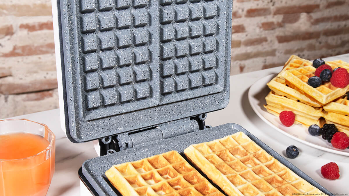 Gofre con gofres dentro y gofres cocidos con bayas en un plato. Ambiente de cocina.