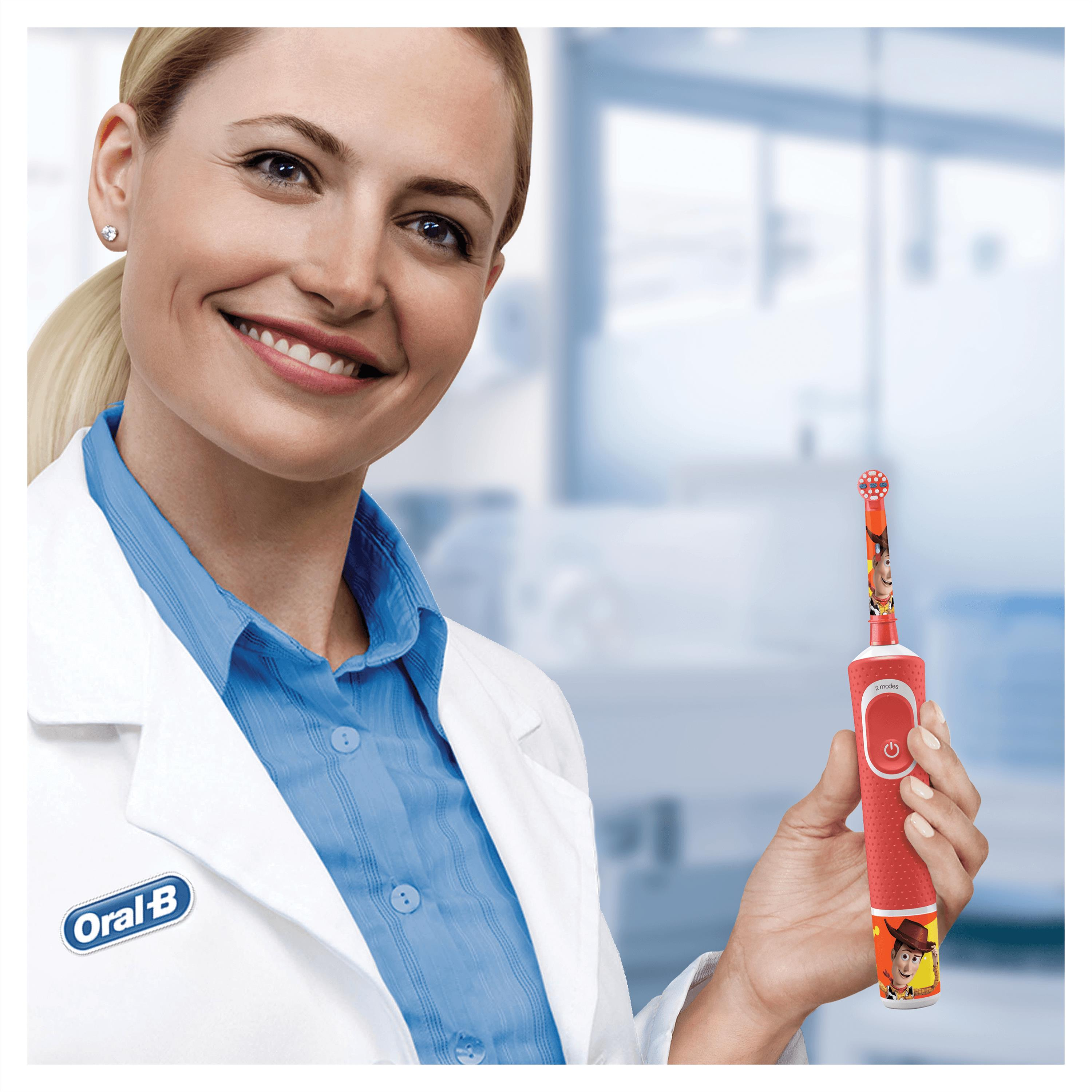 Frau hält eine rote elektrische Zahnbürste von Oral-B mit Toy Story Design.