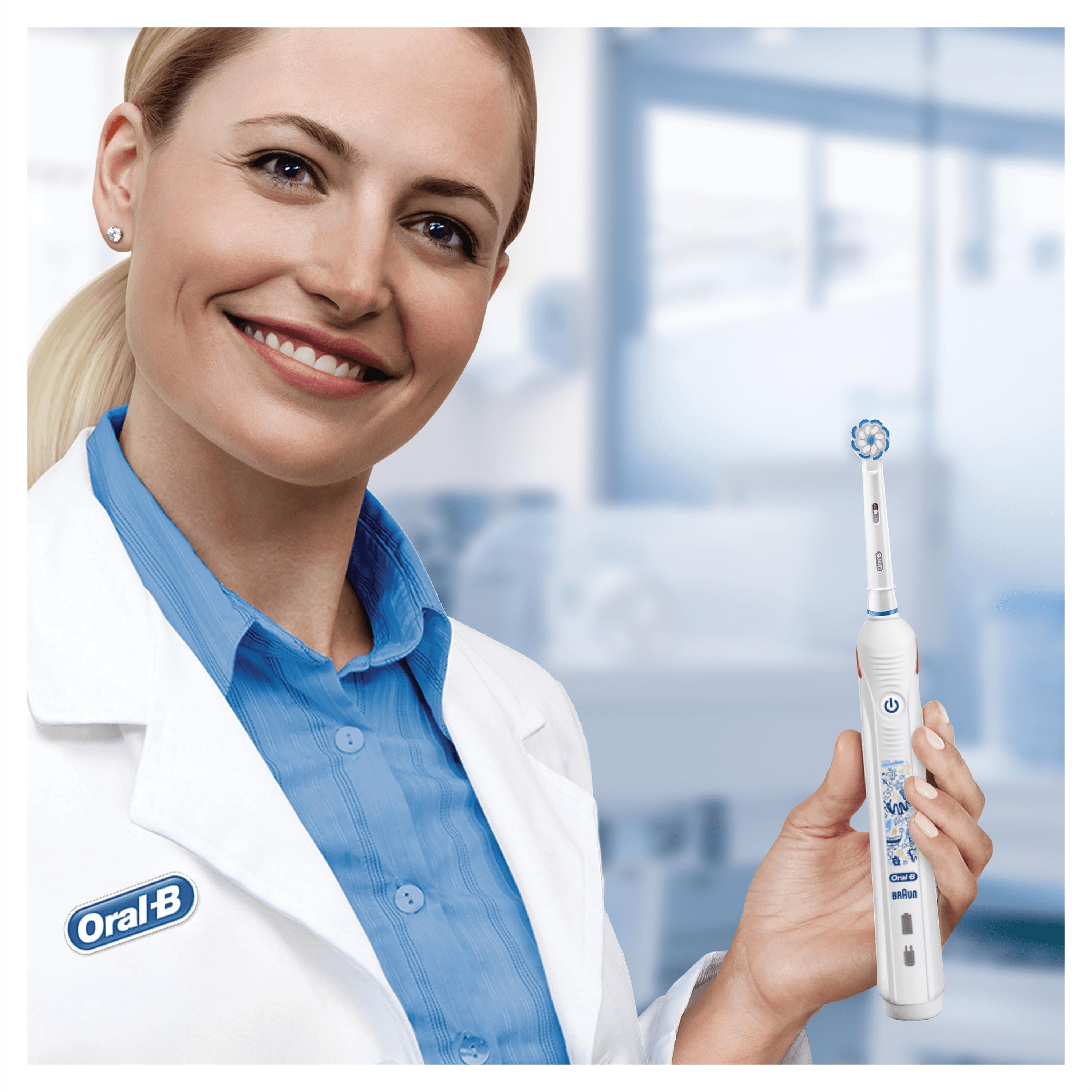 Frau im Laborkittel hält elektrische Zahnbürste. Oral-B Logo sichtbar.