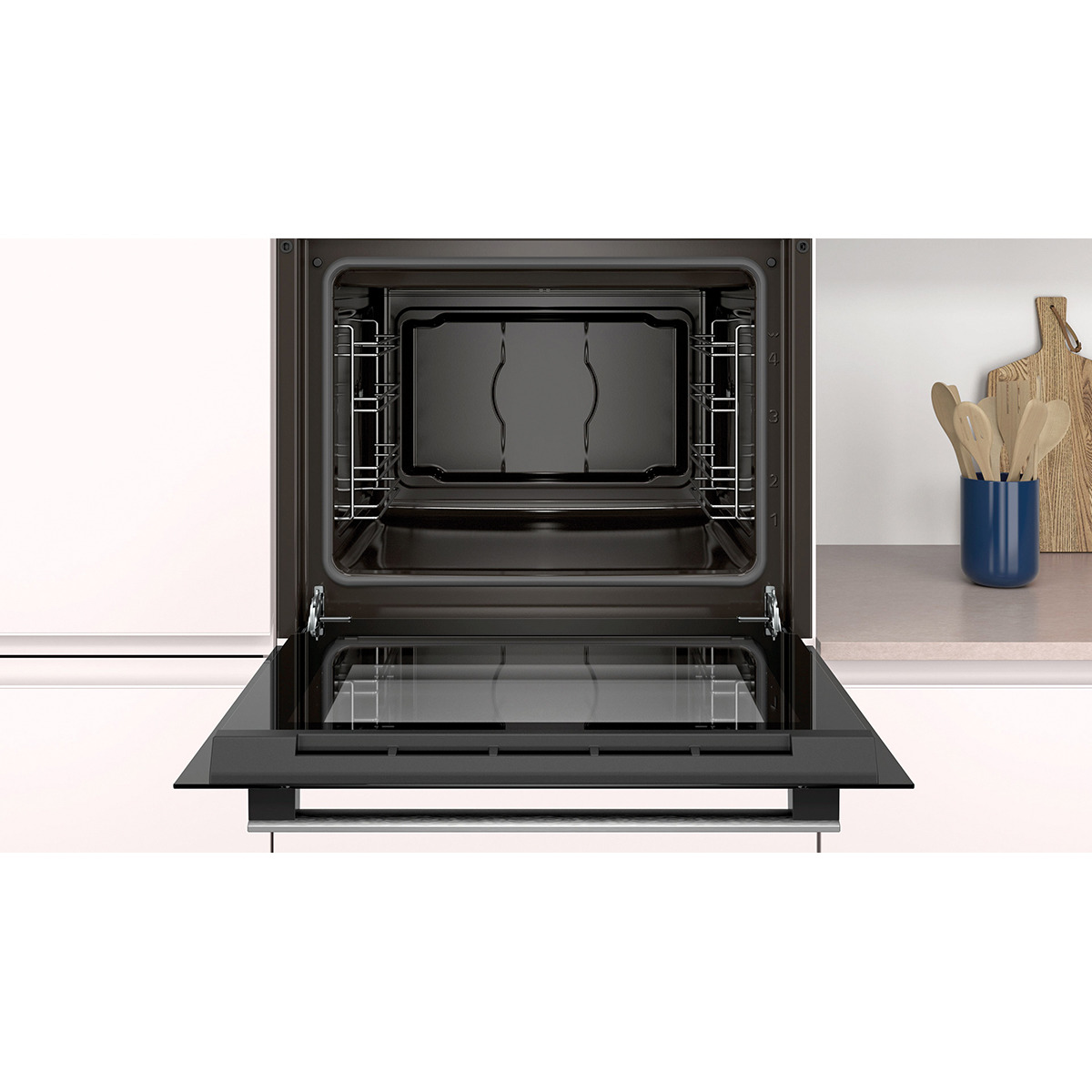 Horno abierto con interior negro, rejillas y puerta de cristal. Ambiente de cocina con tablas de cortar.