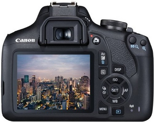 La parte trasera de una cámara Canon, que muestra una pantalla con un paisaje urbano al anochecer.