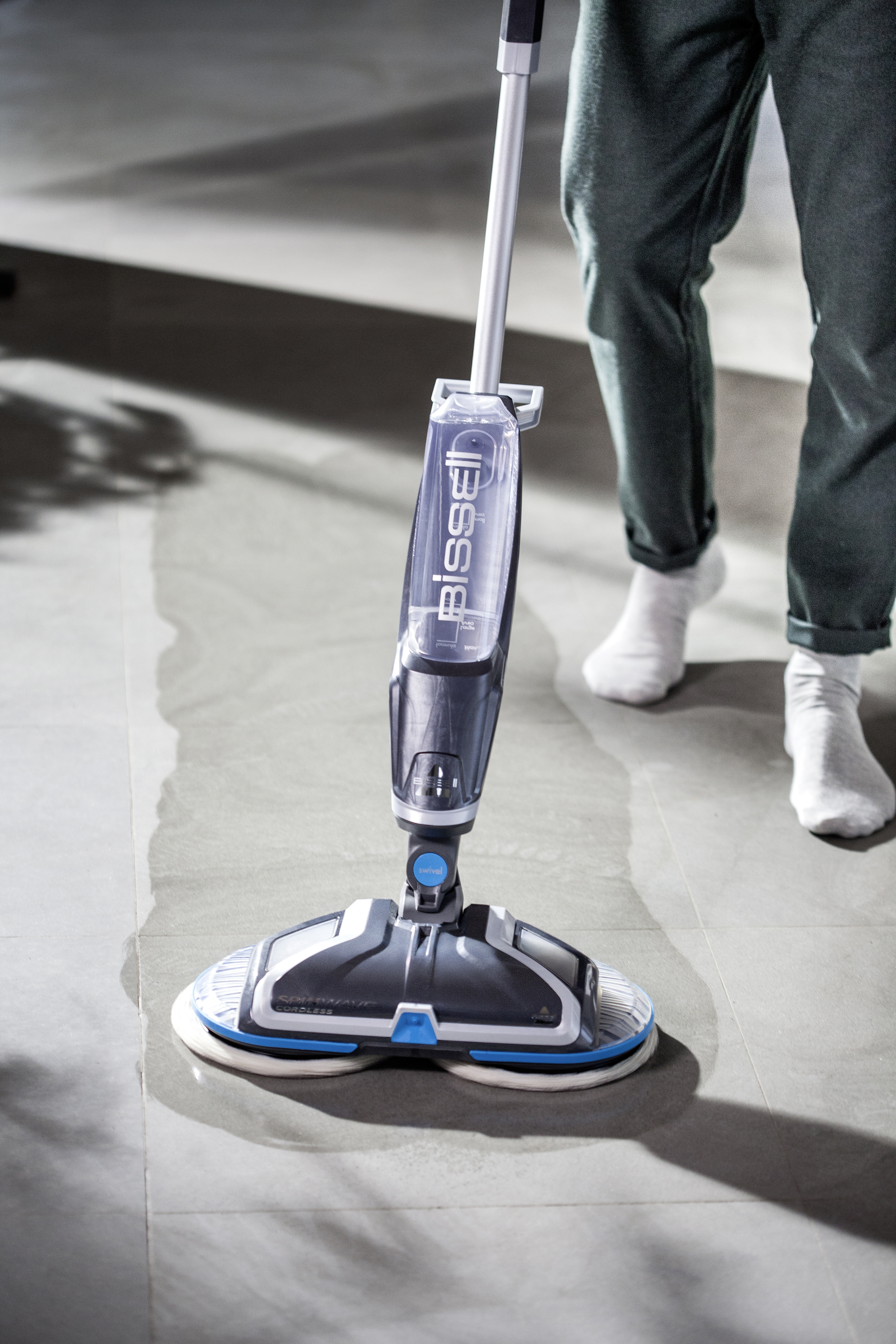 Person wischt einen nassen Boden mit einem Bissell-Spin-Mop, mit Wasserbehälter.