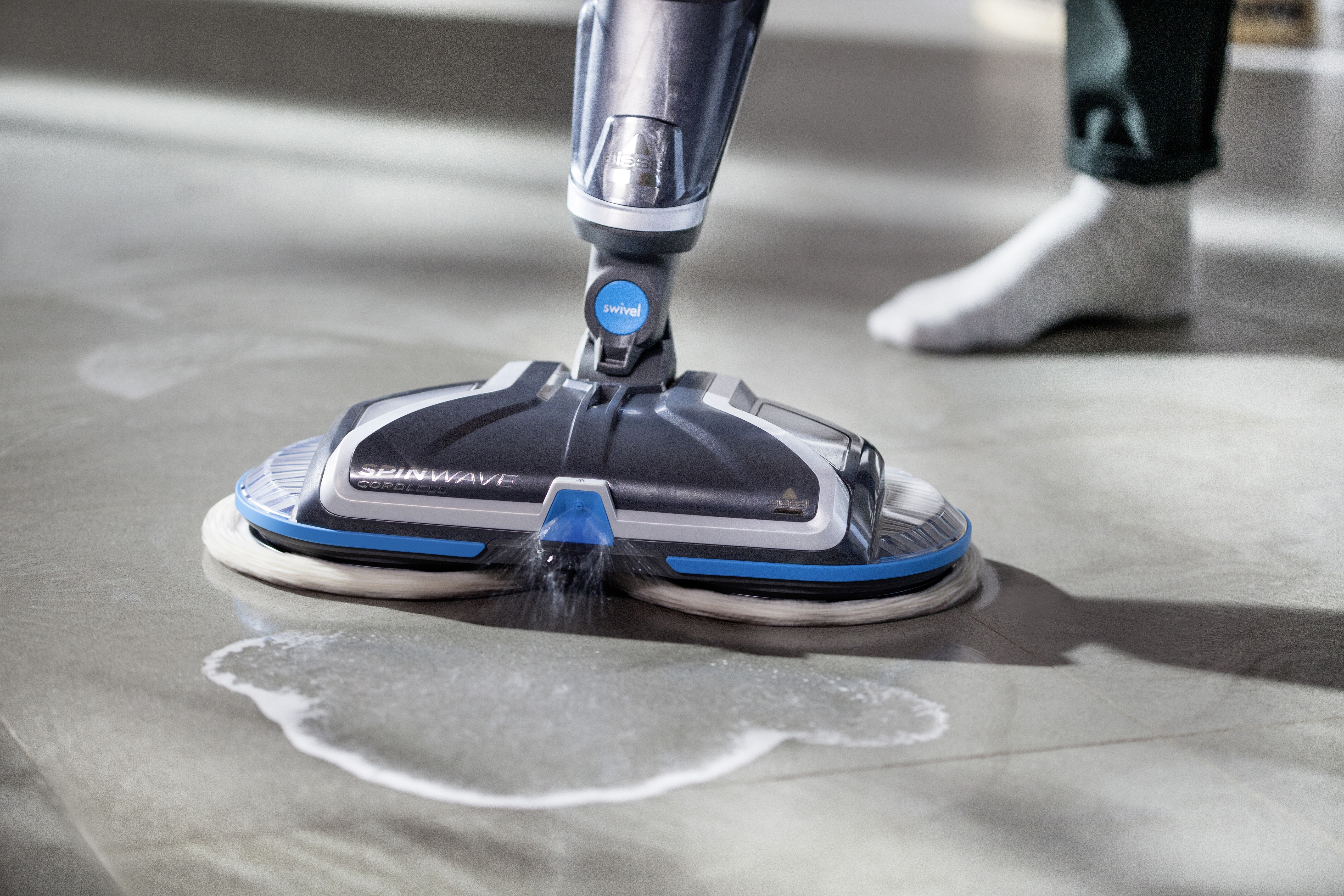 Ein Bodenreiniger mit zwei rotierenden Pads reinigt einen Boden und hinterlässt eine nasse Spur.