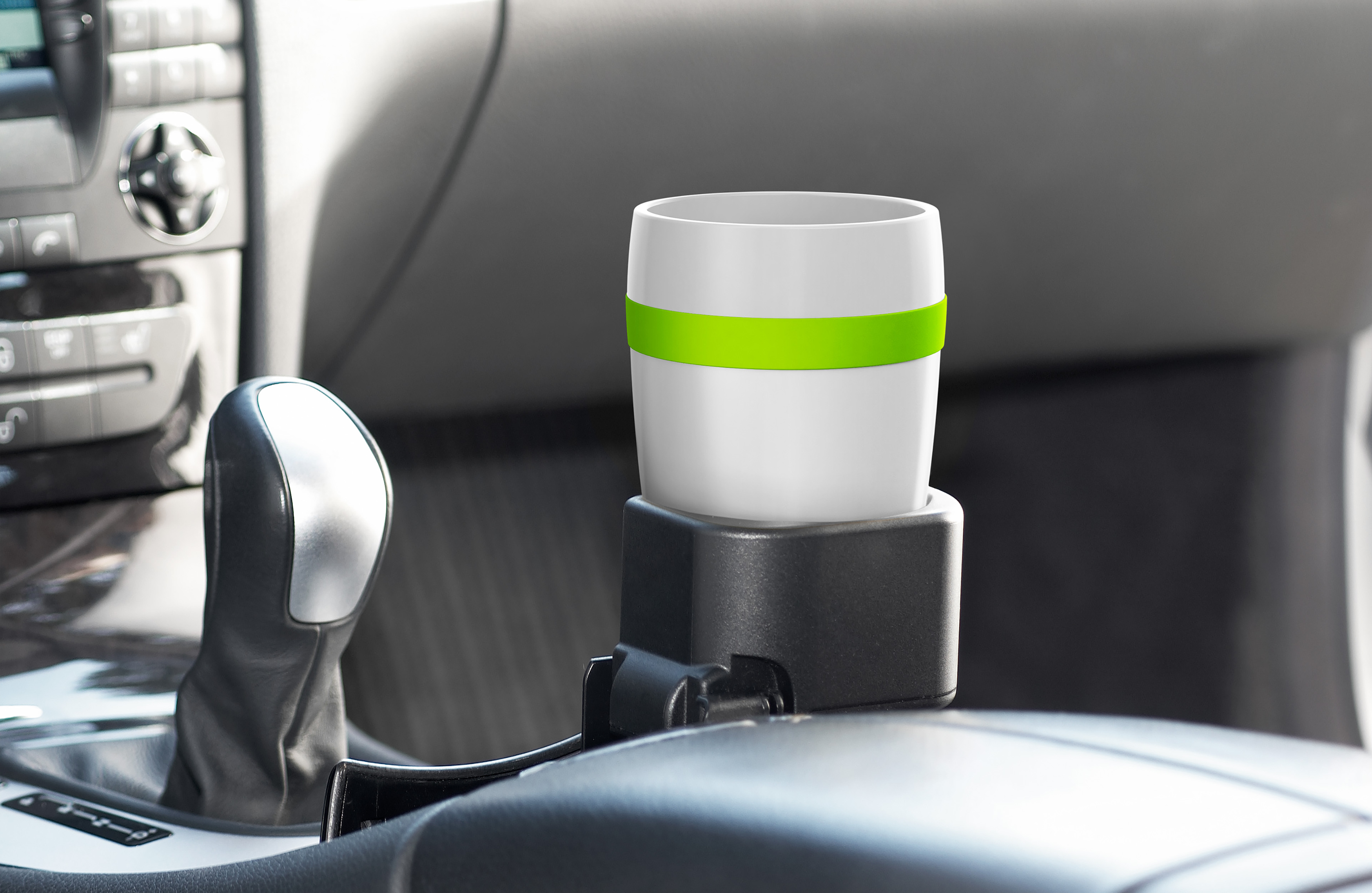 Weißer Reisebecher im Getränkehalter eines Autos, mit grünem Band.
