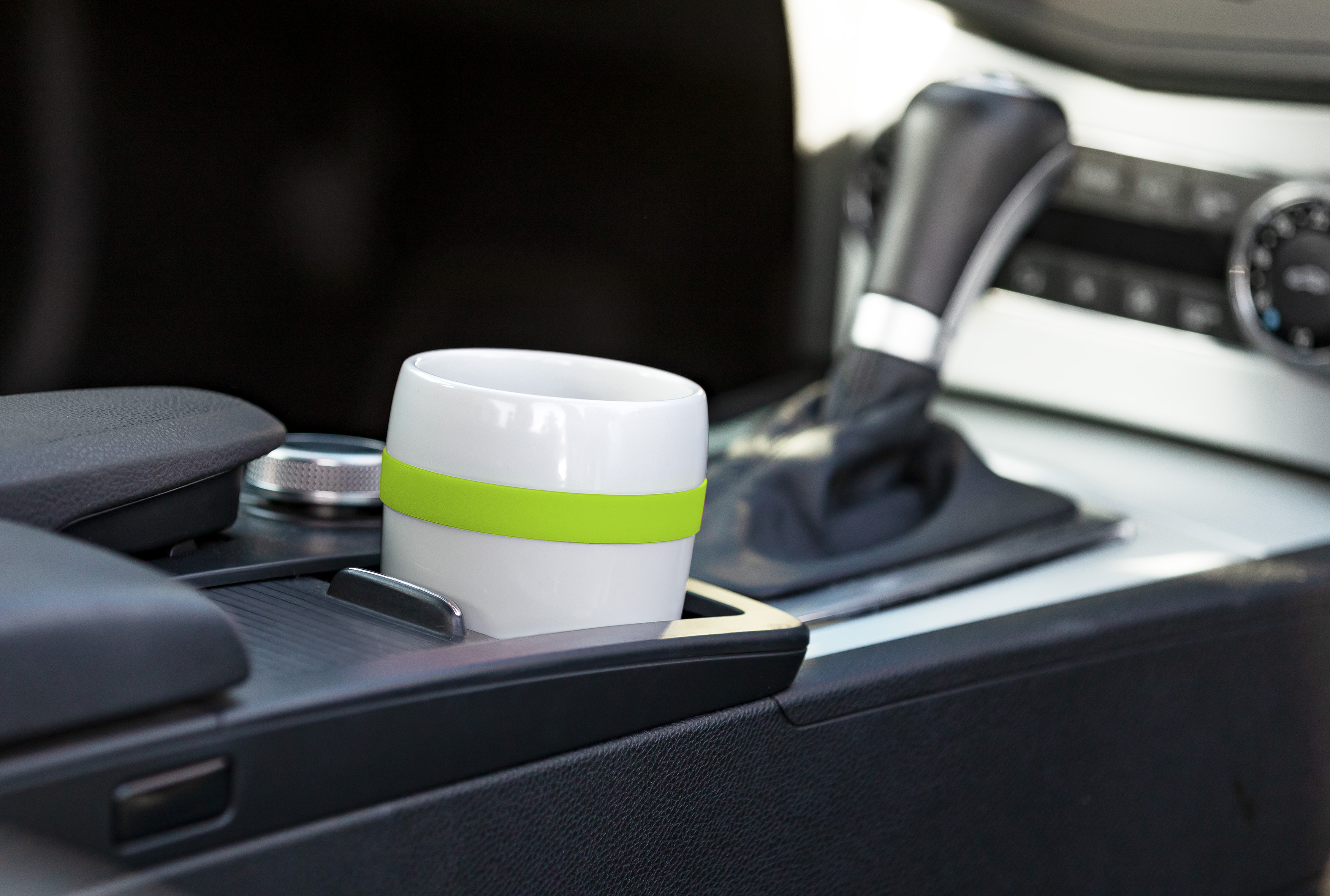 Ein weißer Becher mit grünem Band in der Mittelkonsole eines Autos.