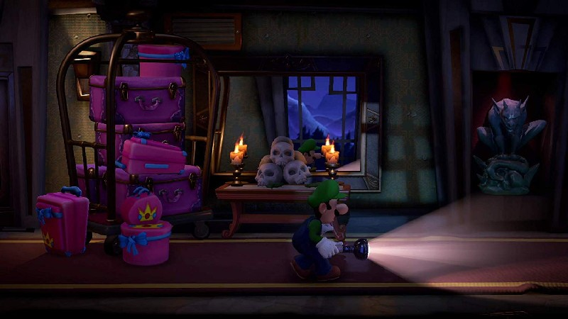 Luigi en un pasillo de hotel embrujado con carrito de equipaje, calaveras y una gárgola.