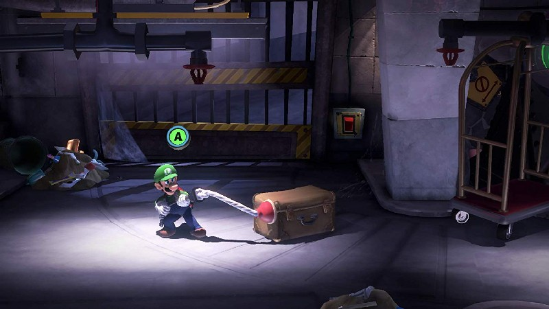 Luigi en un videojuego tirando de una maleta marrón en una habitación con poca luz.