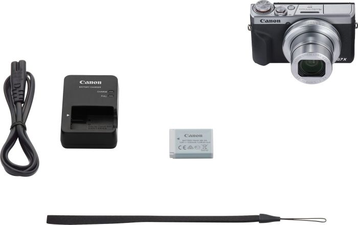 Canon Kamera, Ladegerät, Akku und Handschlaufe auf weißem Hintergrund.