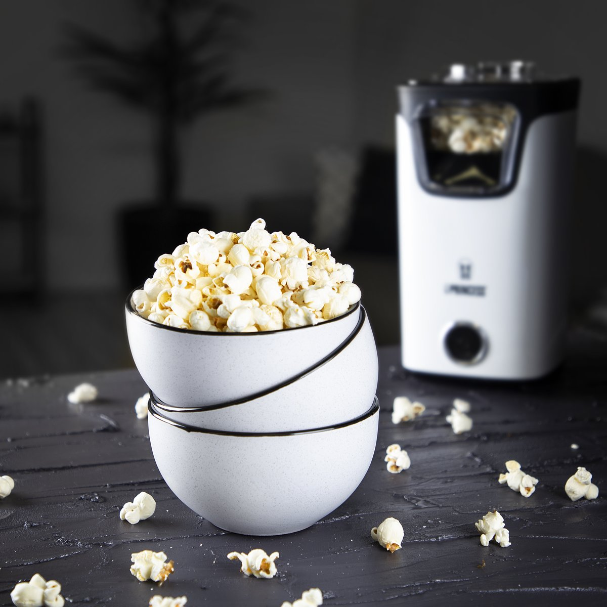 Two bowls filled with popcorn, with a popcorn maker in the background.