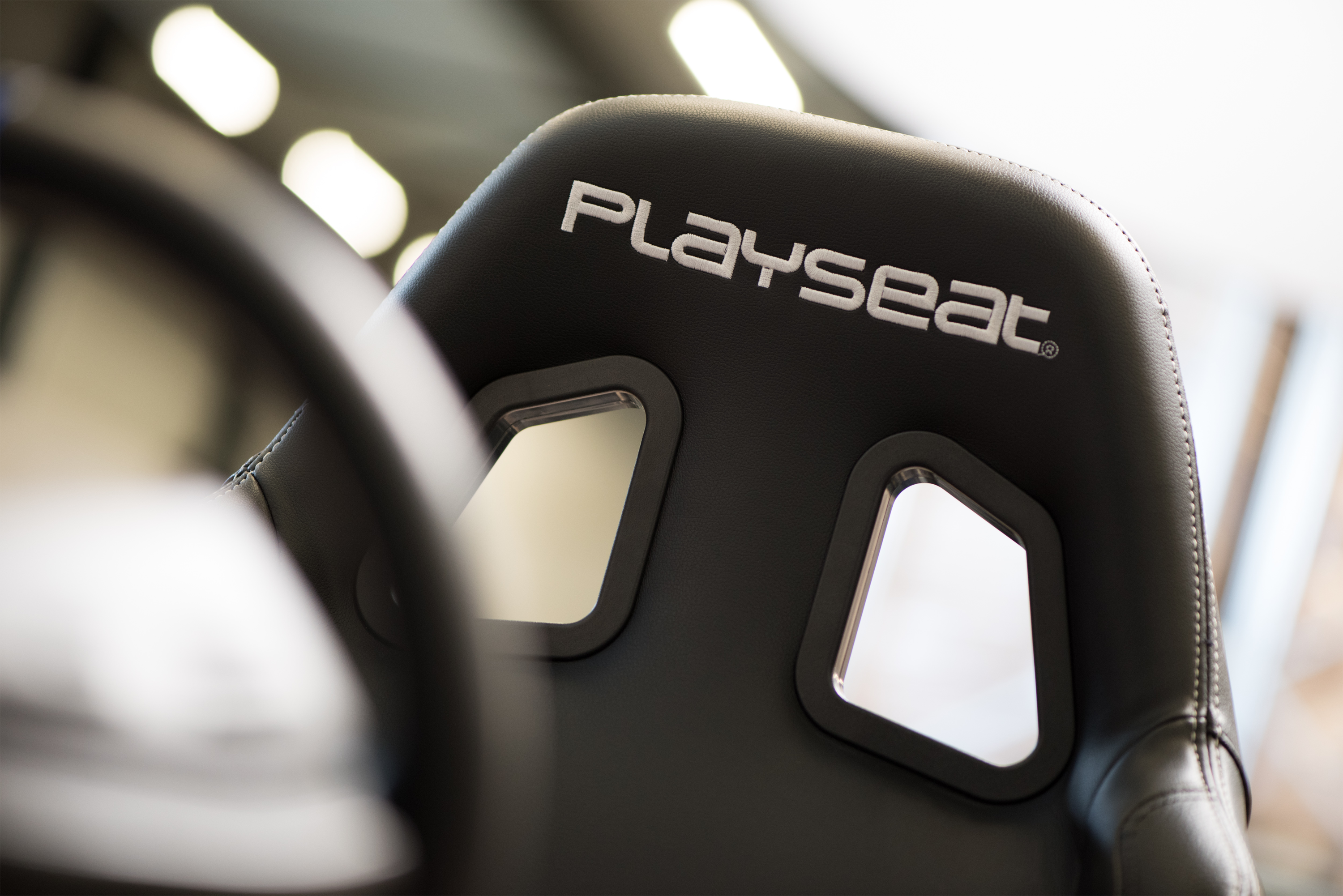 Gros plan sur une chaise de jeu Playseat noire. Le logo est affiché en évidence sur le dossier.