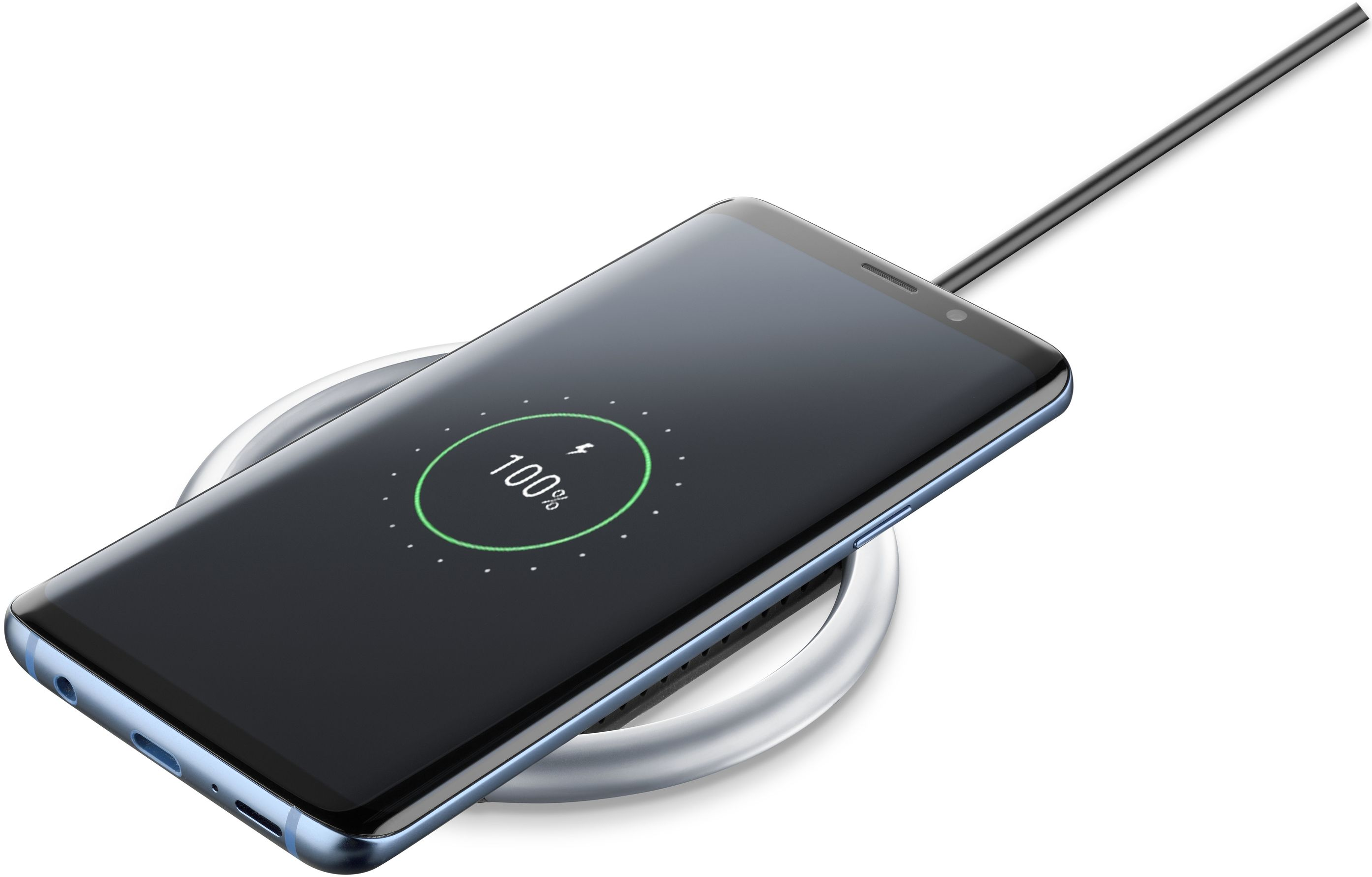 Un telefono si carica su un caricatore wireless argento. Lo schermo mostra il 100%.