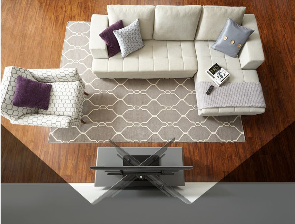 Vue aérienne d'un salon avec canapé sectionnel, tapis, TV et fauteuil.