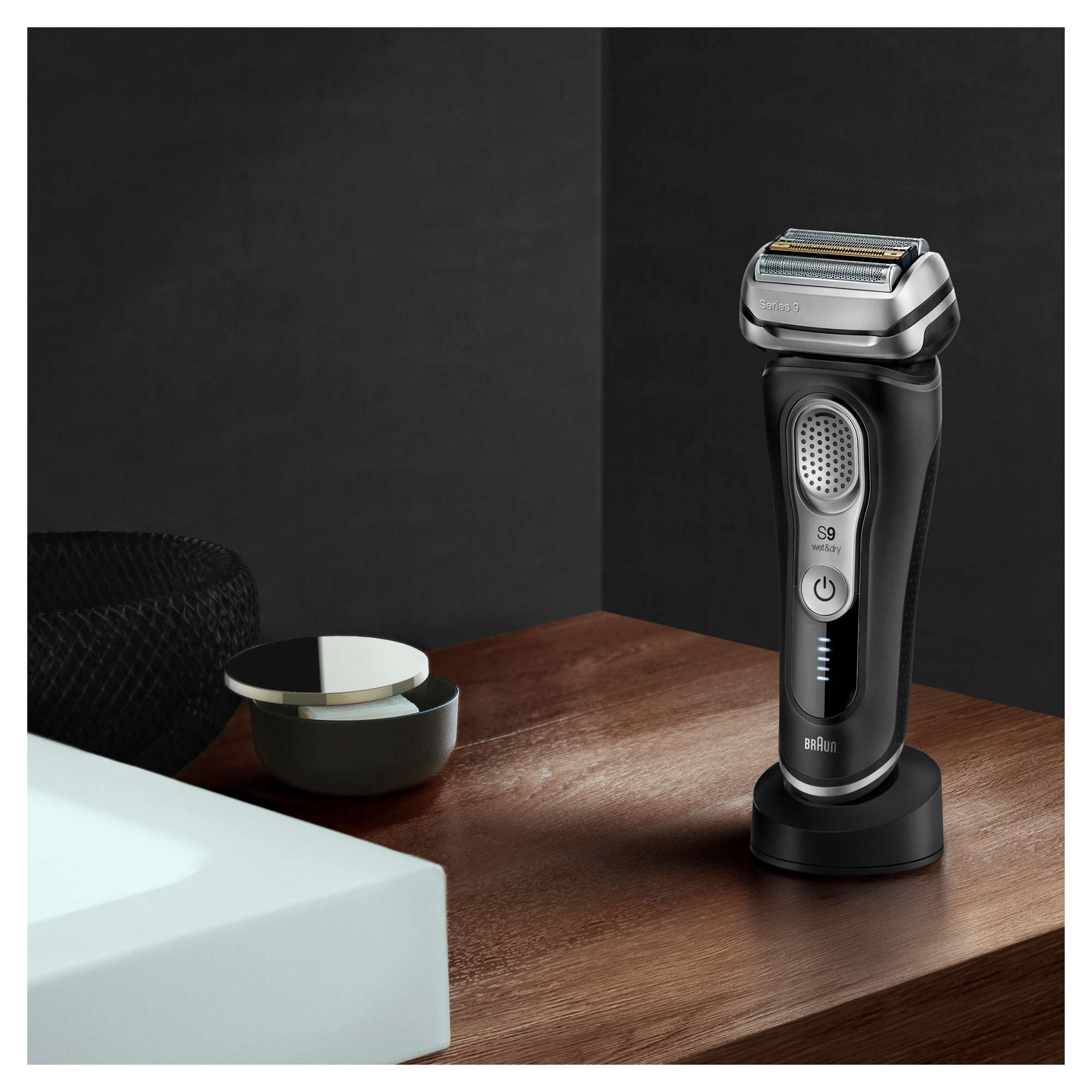 Schwarzer und silberner elektrischer Rasierer Braun Series 9 auf Ständer mit Zubehör.