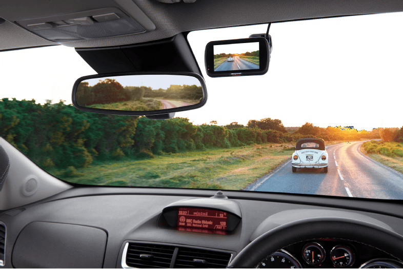 View from a car interior, showing a dashboard, rearview mirror, and a road ahead with a car.