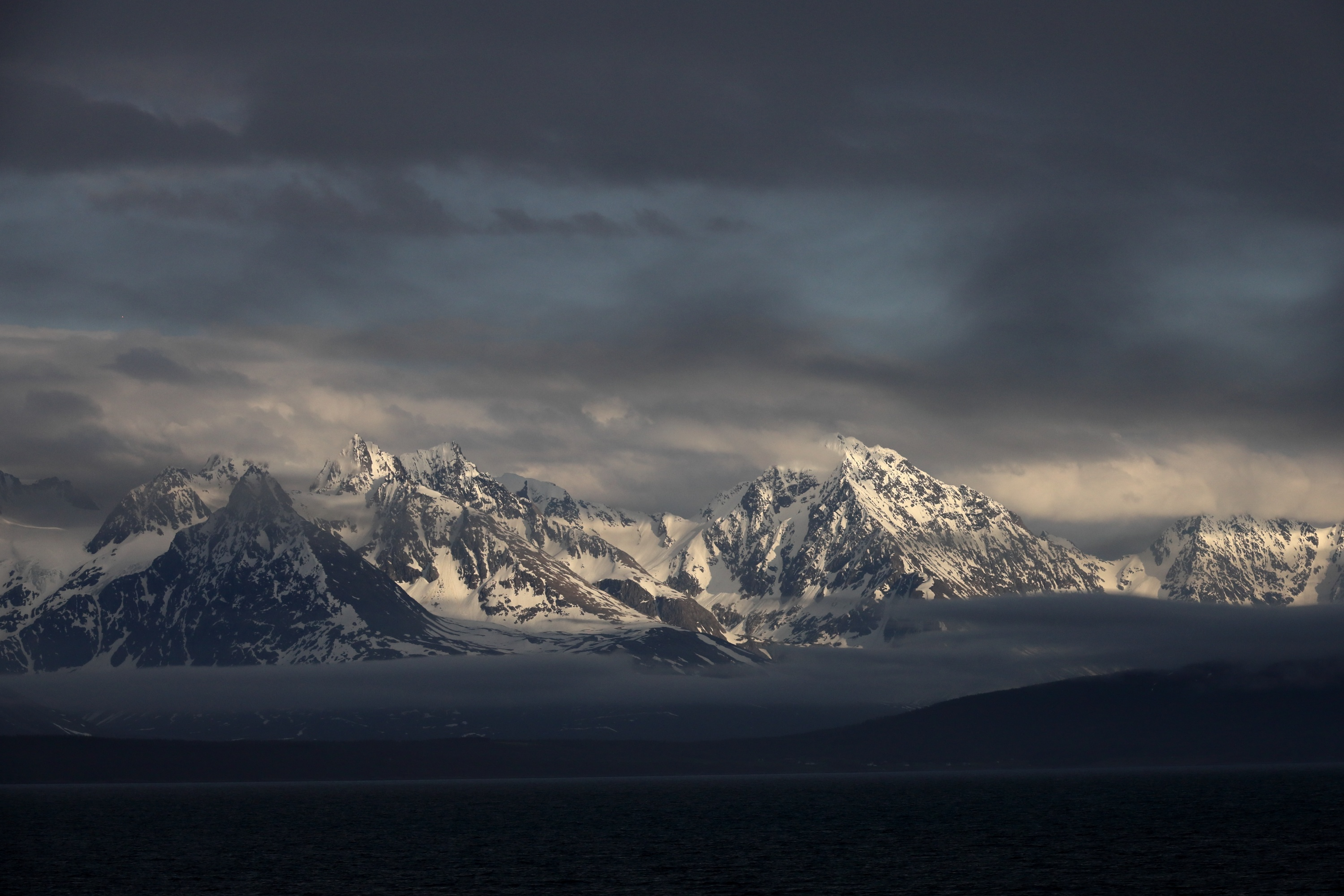 Eine malerische Aussicht auf schneebedeckte Berge unter bewölktem Himmel.